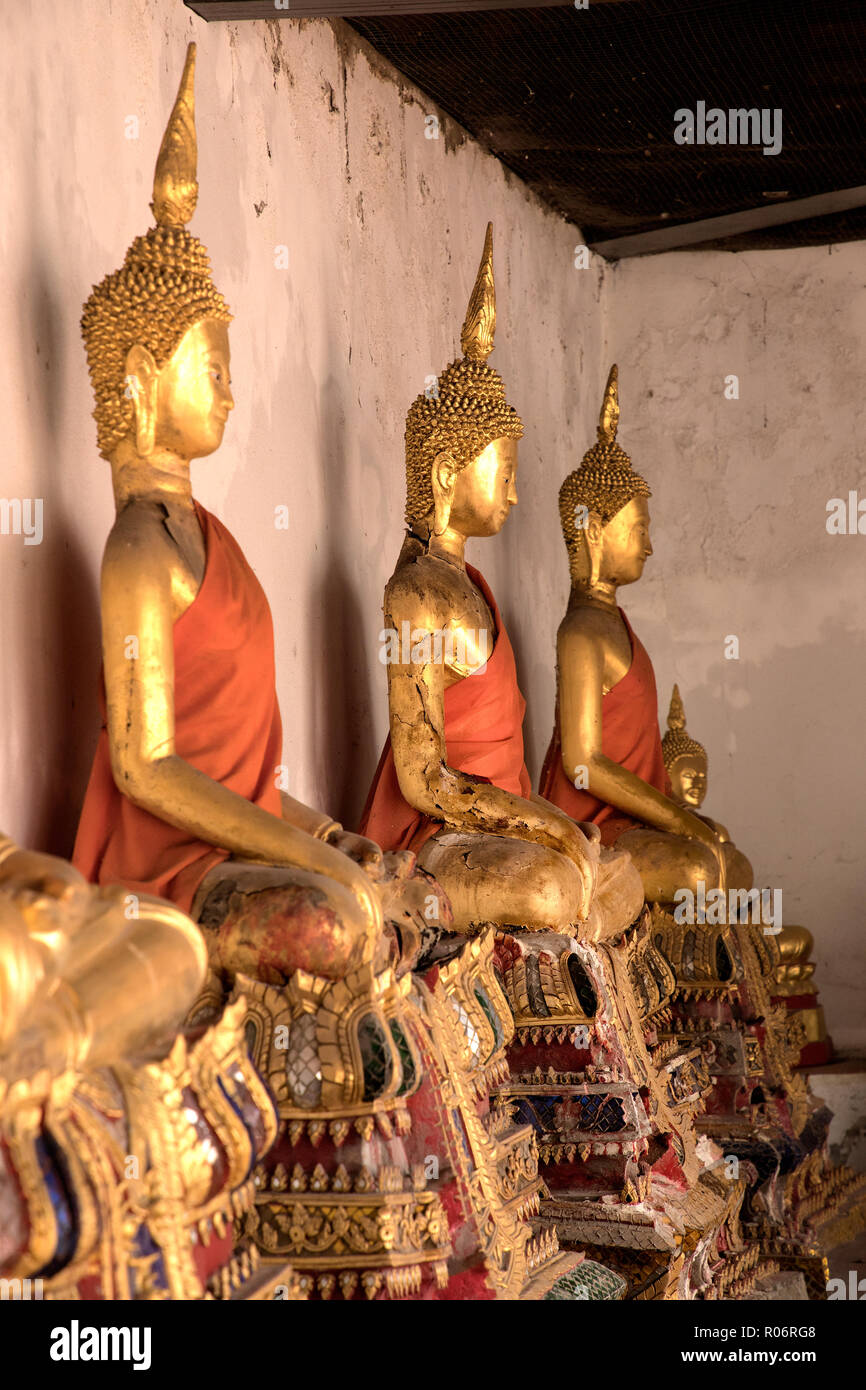 Close up shiny golden buddha statues in a row with beam of light in