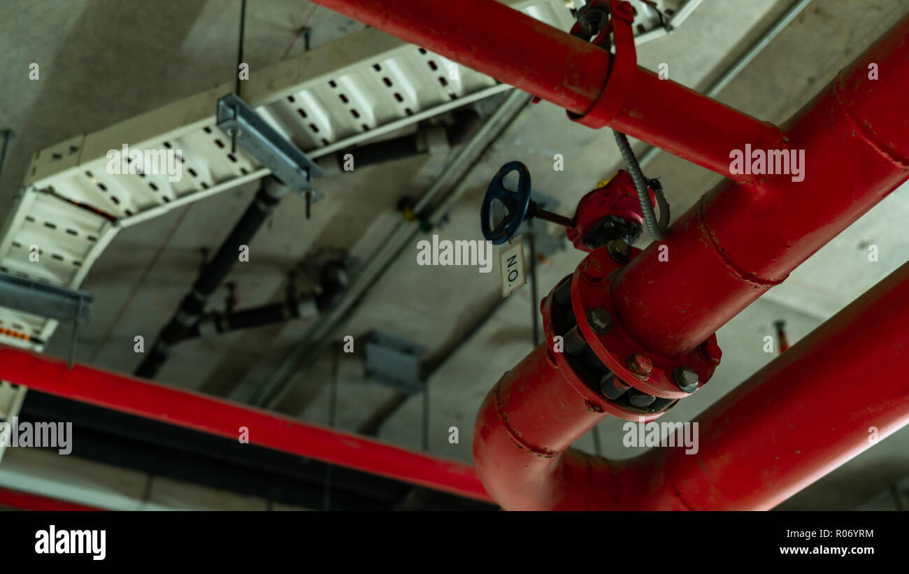 Fire sprinkler system with red pipes hanging from ceiling inside