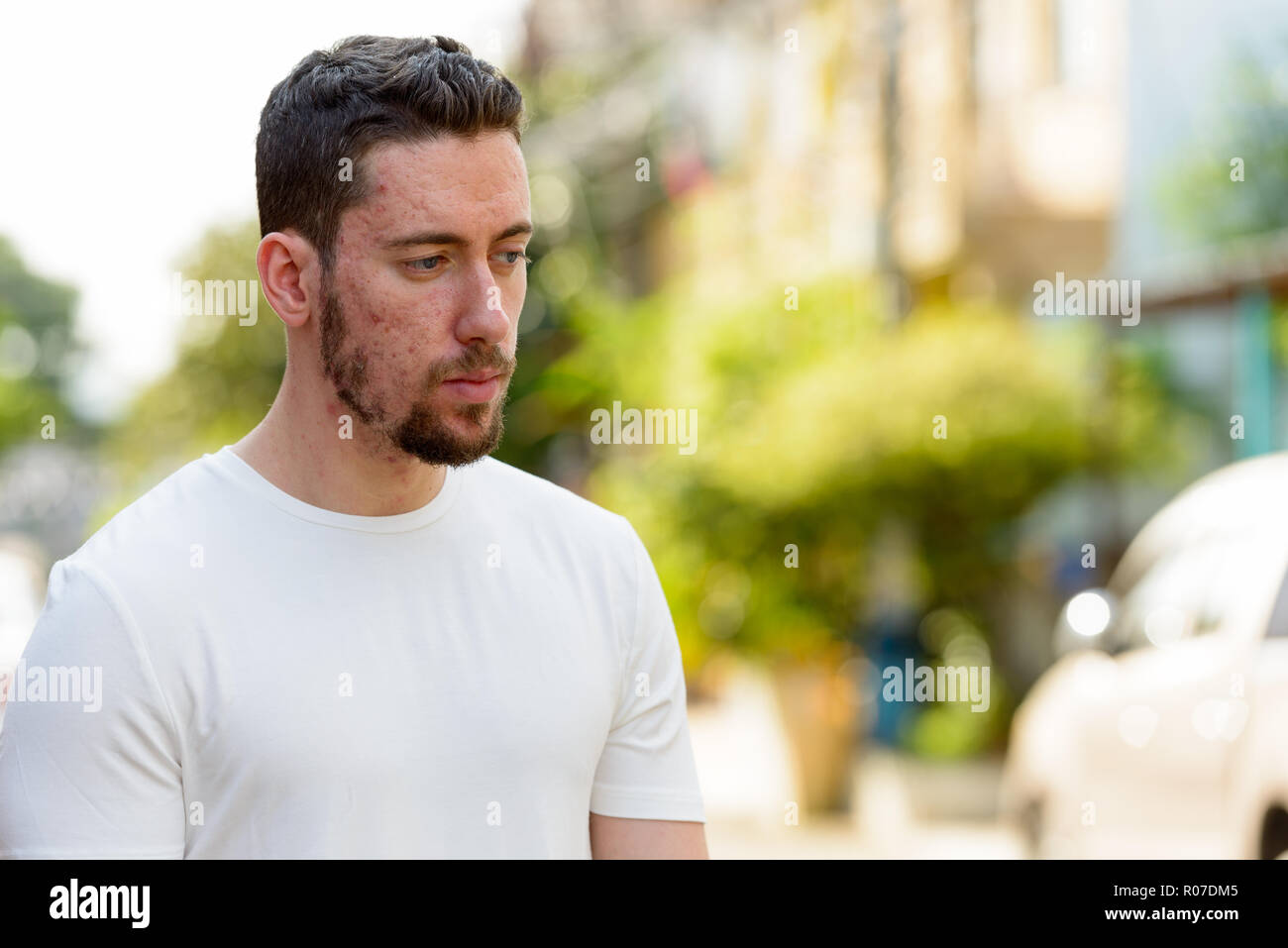 Portrait of young thoughtful man looking down outdoors Stock Photo