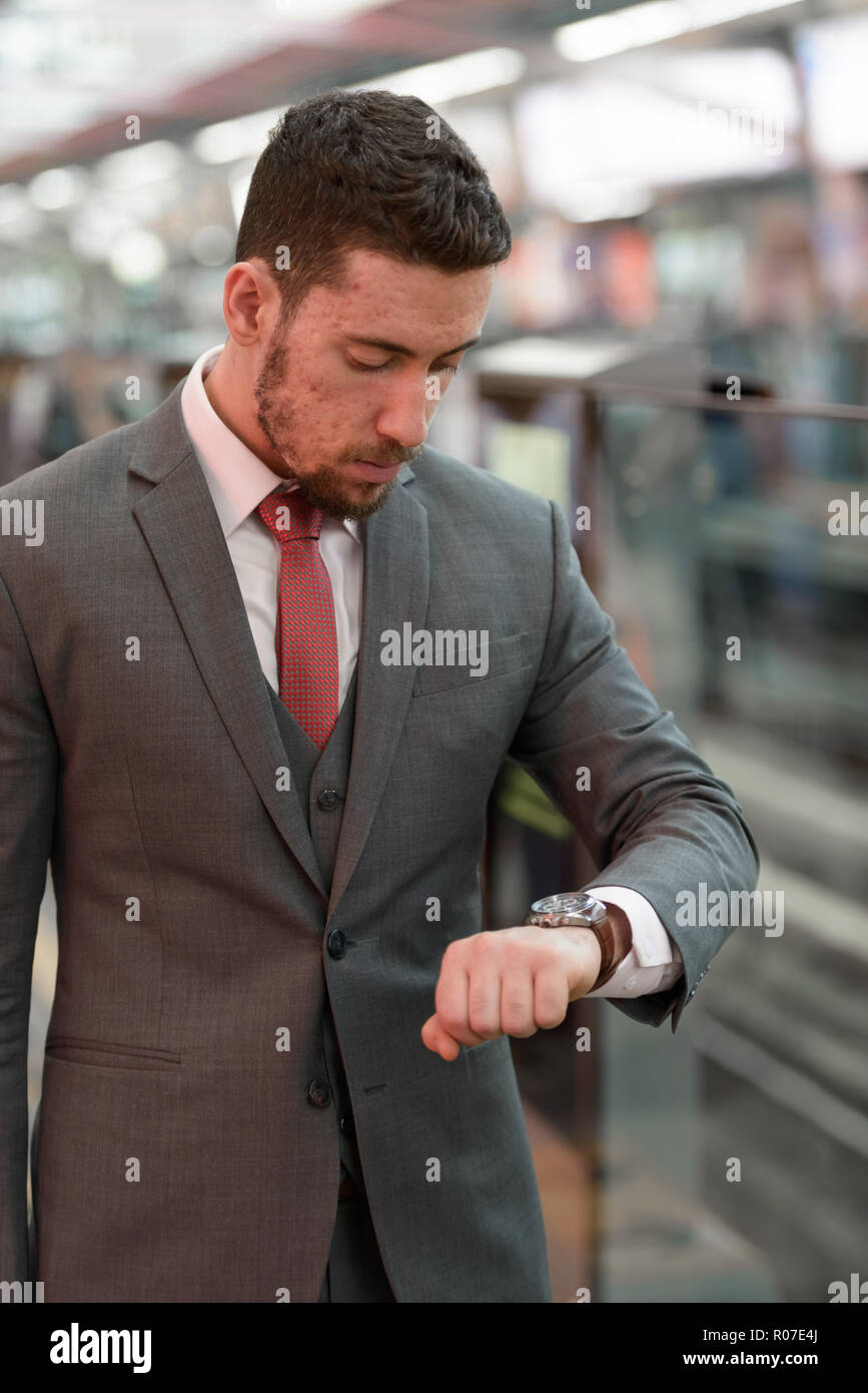 Young handsome Caucasian businessman looking watch at train stat Stock Photo