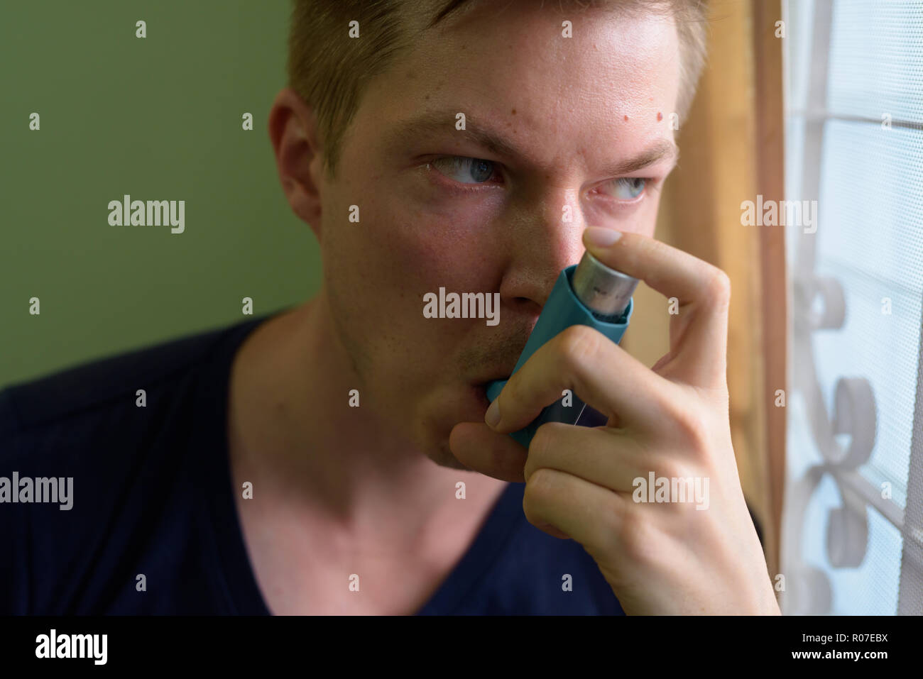 Young handsome man using asthma inhaler at home Stock Photo