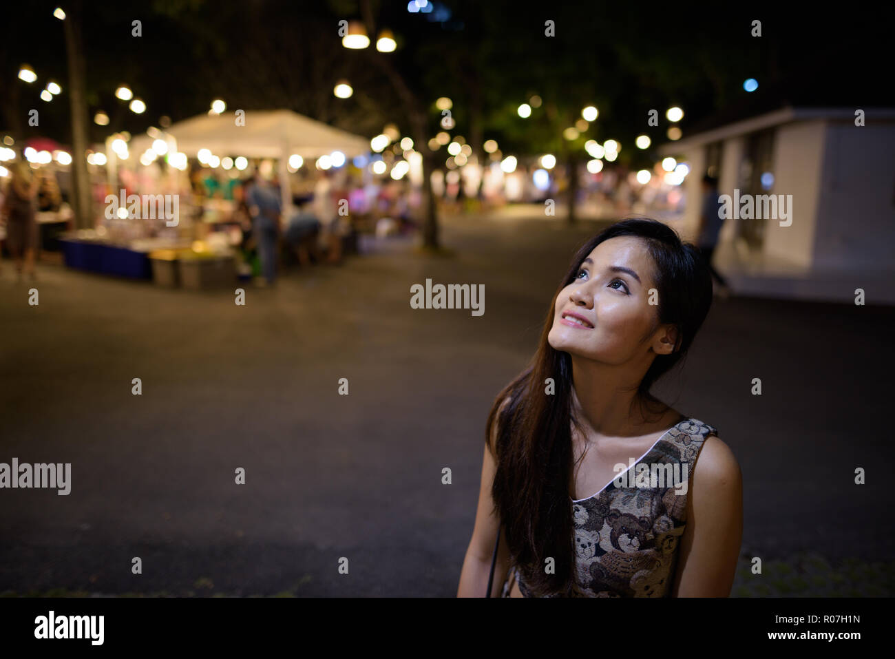 Young happy beautiful Asian woman smiling and thinking against t Stock Photo