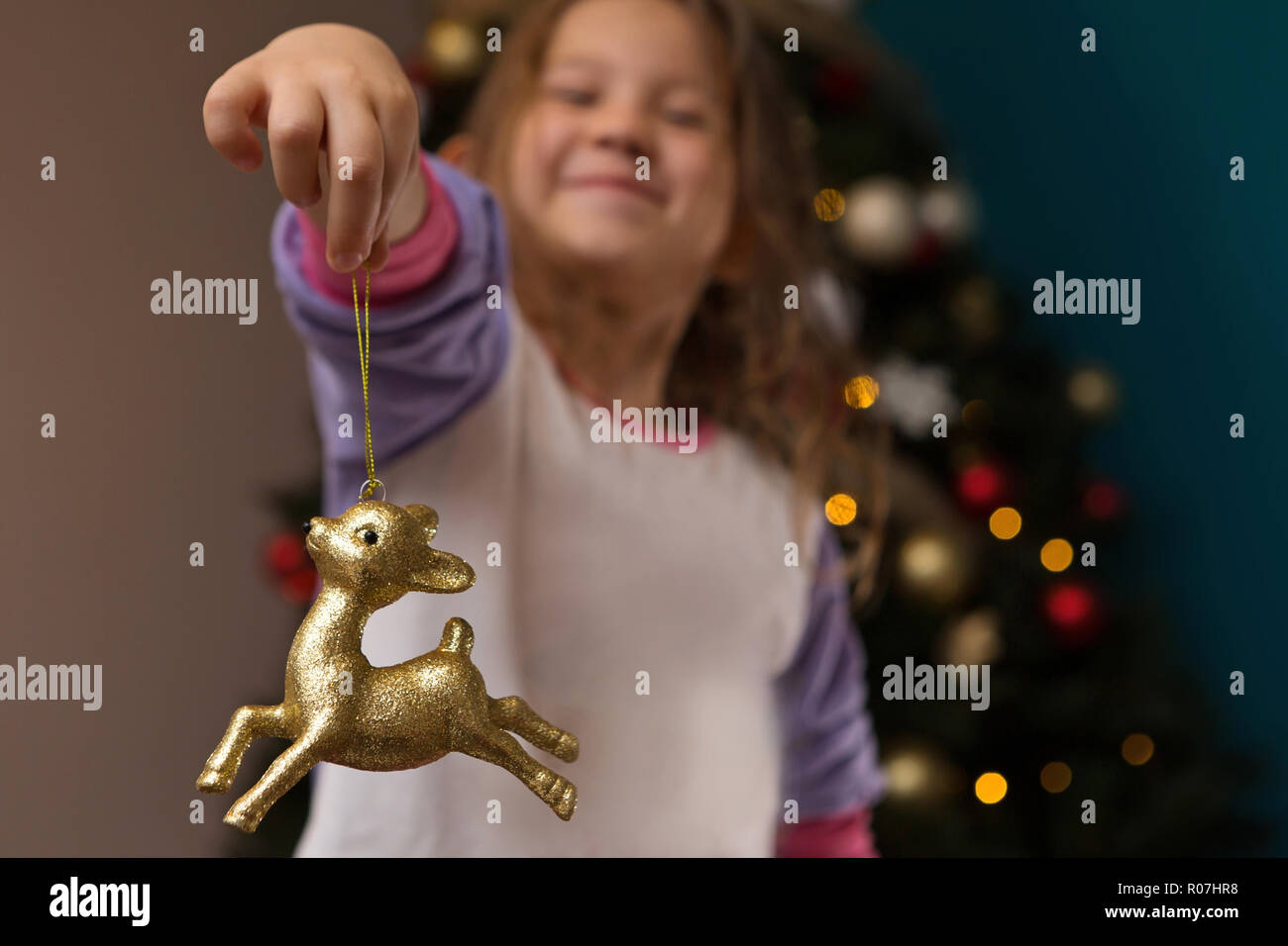 Happy Young Girl Smiling Holding Gold Reindeer Ornament Stock Photo