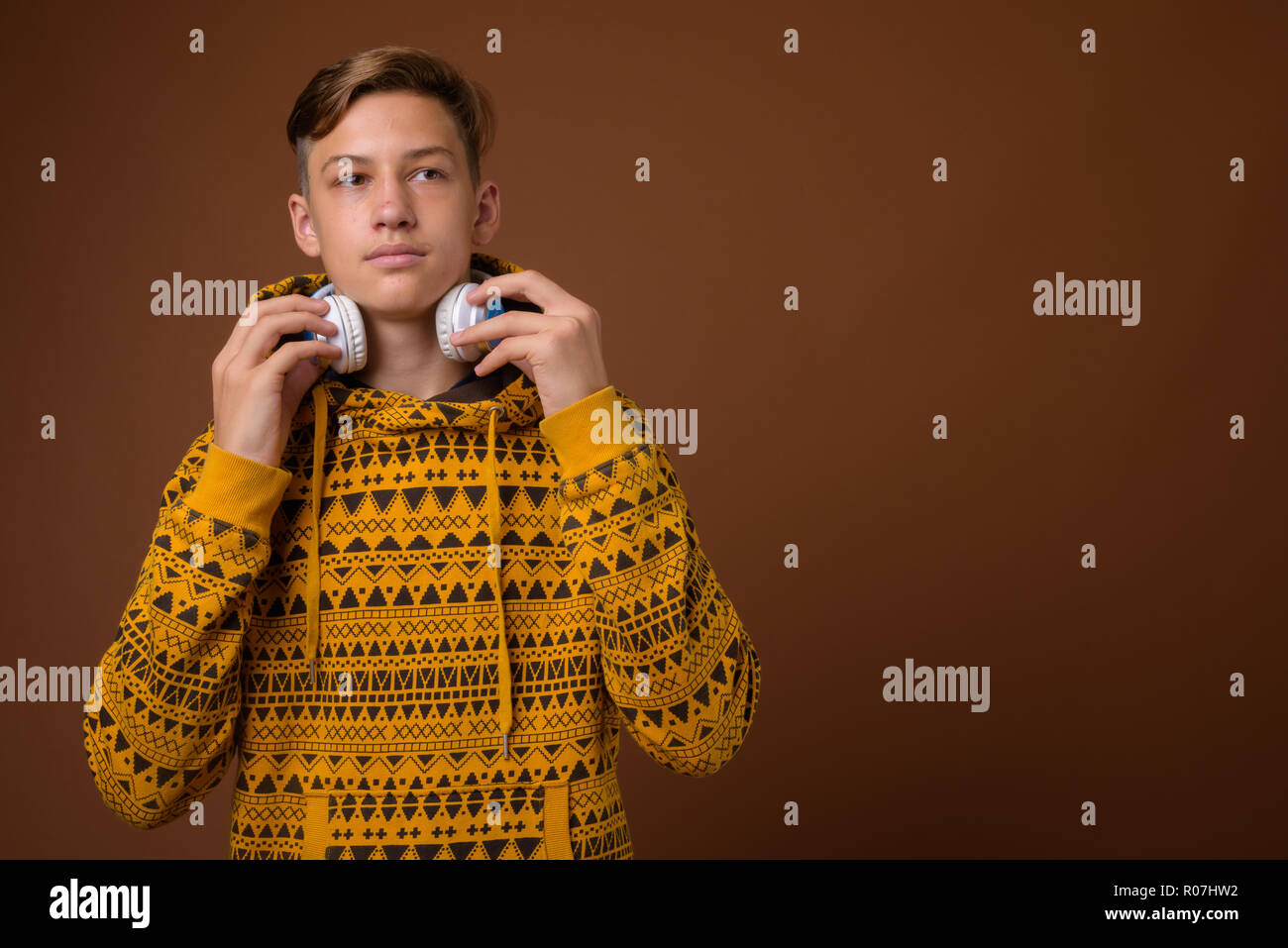 Studio shot of young handsome teenage boy against brown backgrou Stock Photo