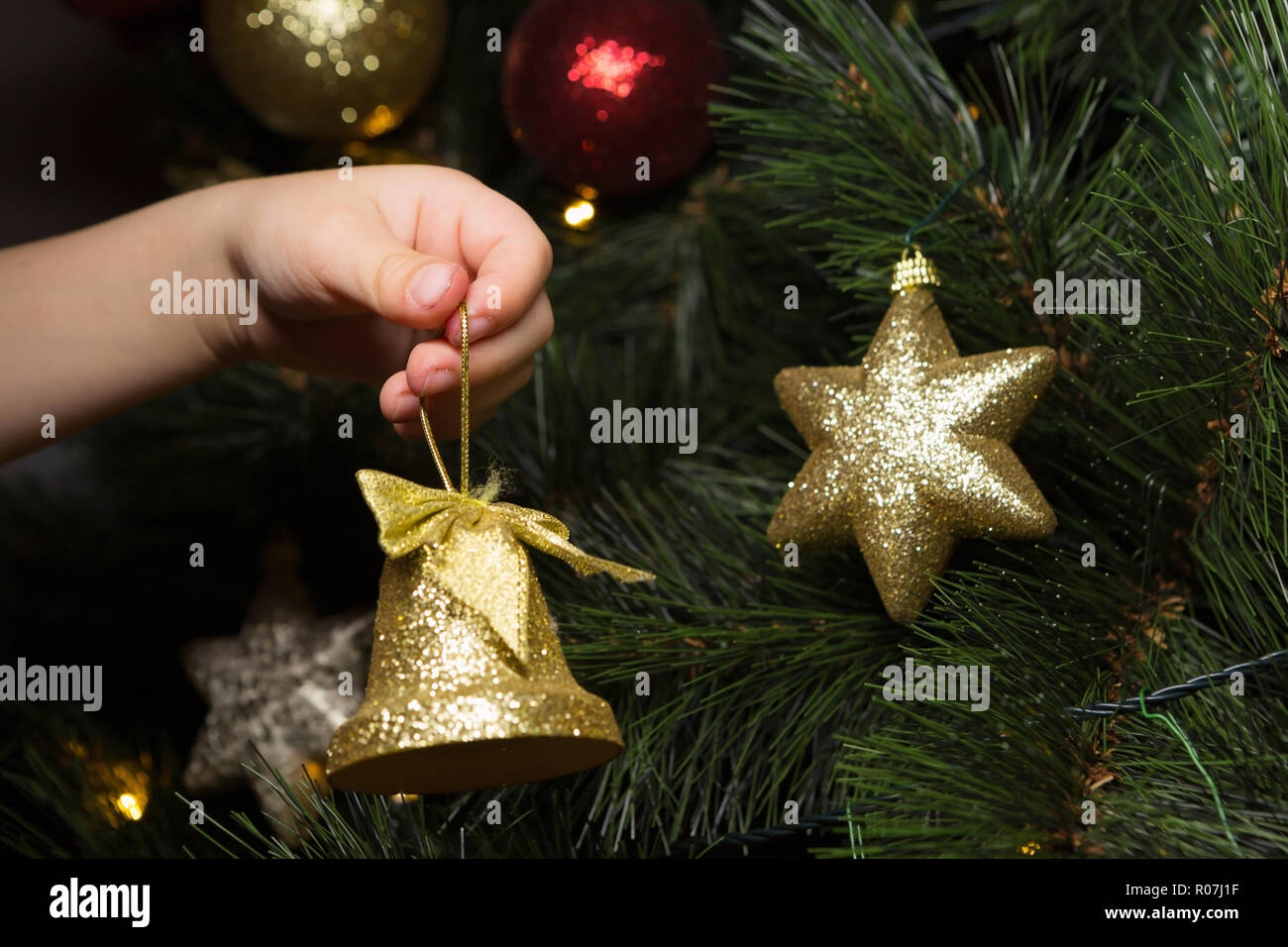 Close-up of Childâ€™s Hand Putting a Christmas Ornament on the Tree Stock Photo