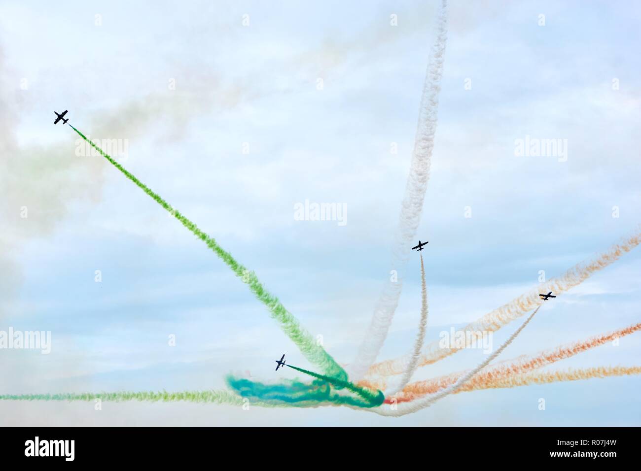 Fighter jets in action during a show. A group of italian fighter jets with colors white, orange and green of the italian flag agains a cloudy sky. Stock Photo