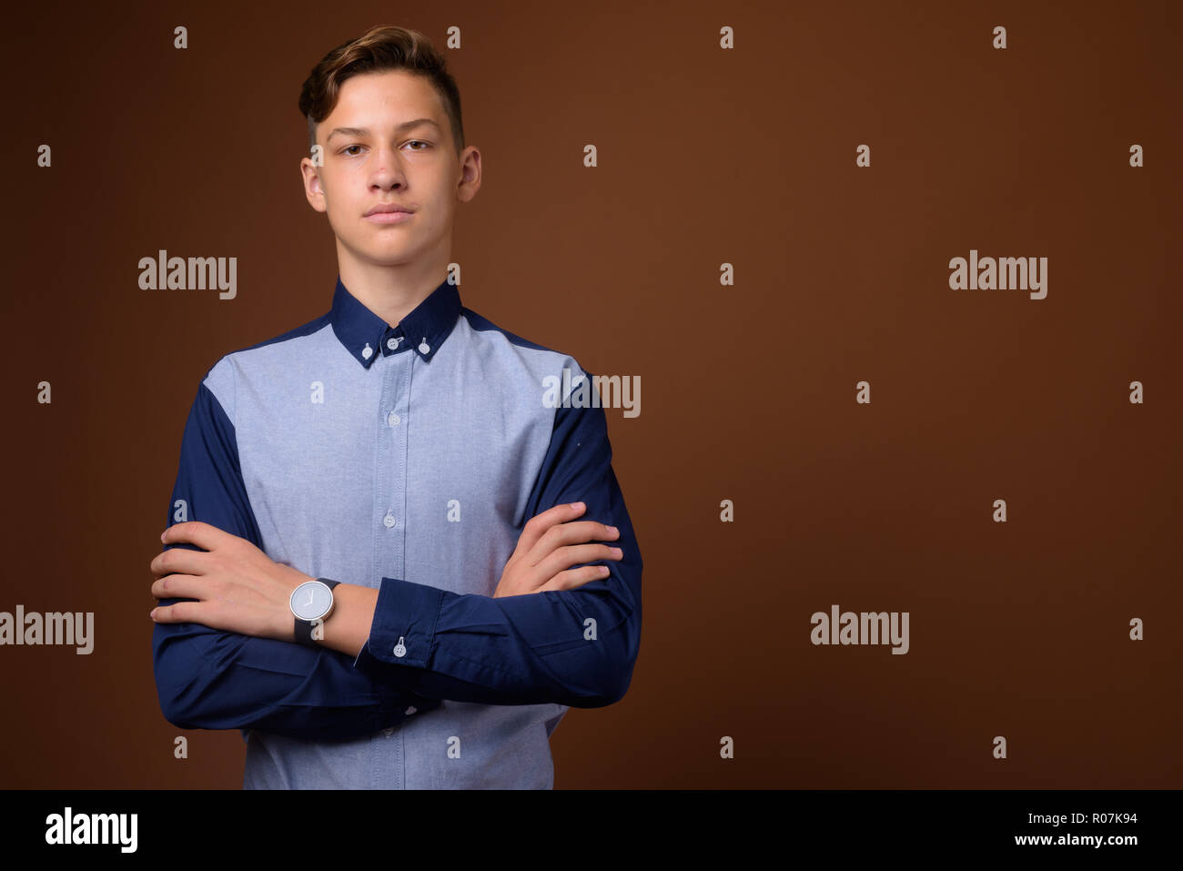 Studio shot of young handsome teenage boy against brown backgrou Stock Photo