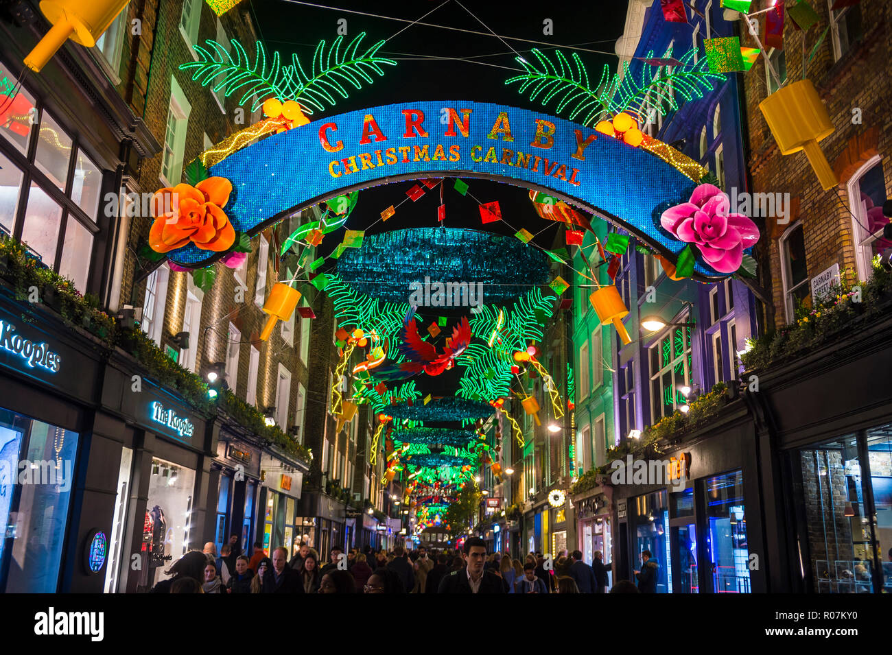 LONDON - CIRCA DECEMBER, 2017: Holiday crowds pass under Carnival themed Christmas signs in the pedestrianized shopping district of Carnaby Street. Stock Photo