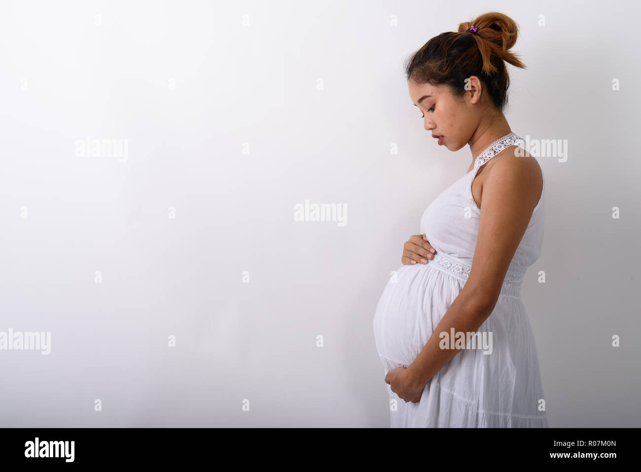 Profile view of young Asian pregnant woman holding her stomach a Stock Photo