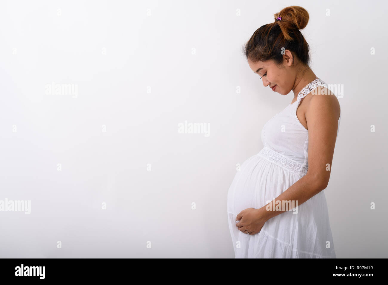 Profile view of young Asian pregnant woman holding while looking Stock Photo