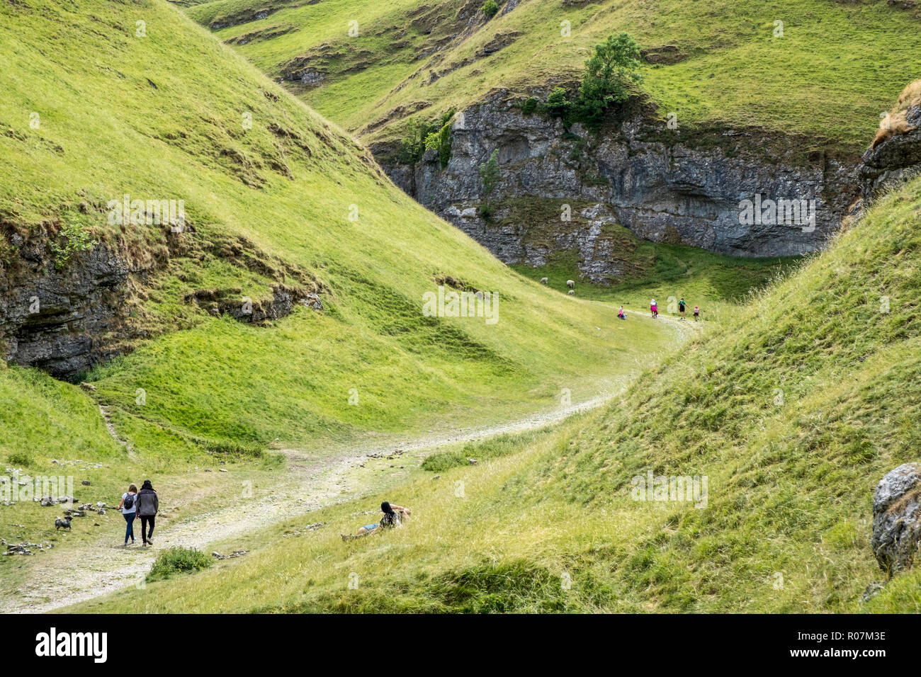 Hikers walking along the Limestone Way and people relaxing in Cave Dale, near Castleton, Derbyshire, Peak District, England, UK Stock Photo