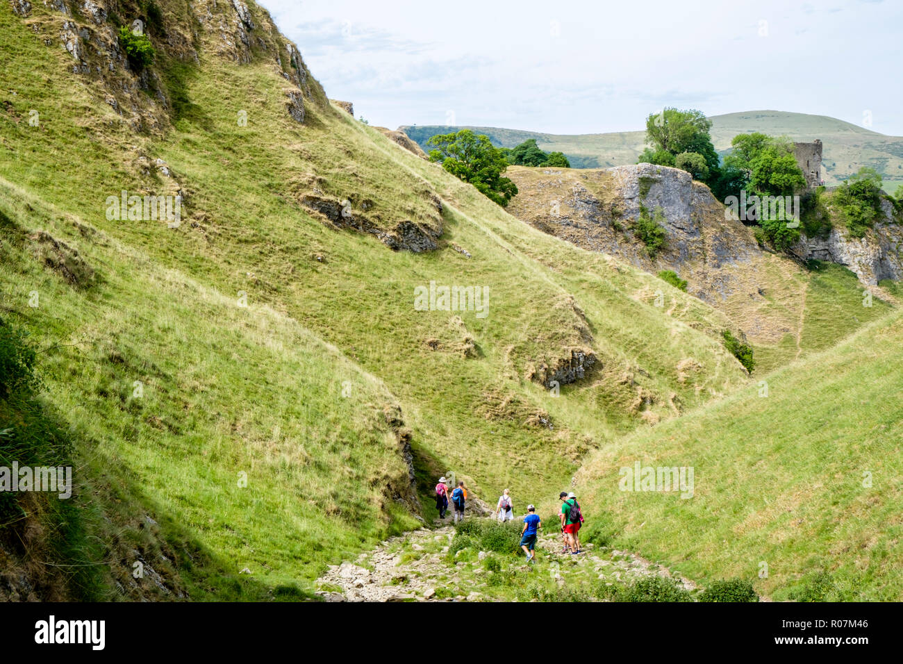People in the Derbyshire countryside. Walkers on the Limestone Way in Cave Dale with Peveril Castle in the distance, Derbyshire, Peak District, UK Stock Photo
