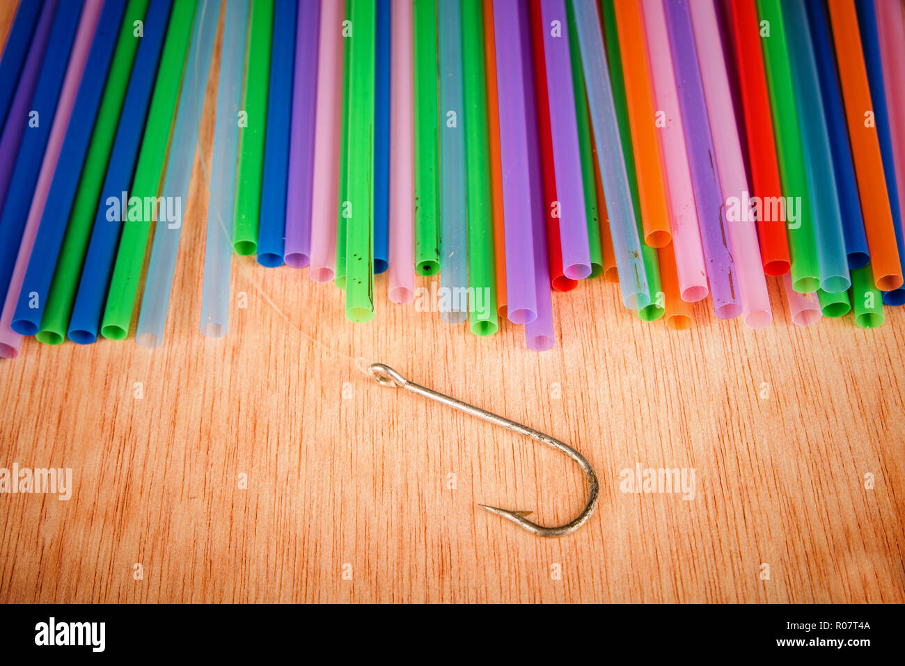 Fishing hook surrounded by drinking straws, a concept of the pollution