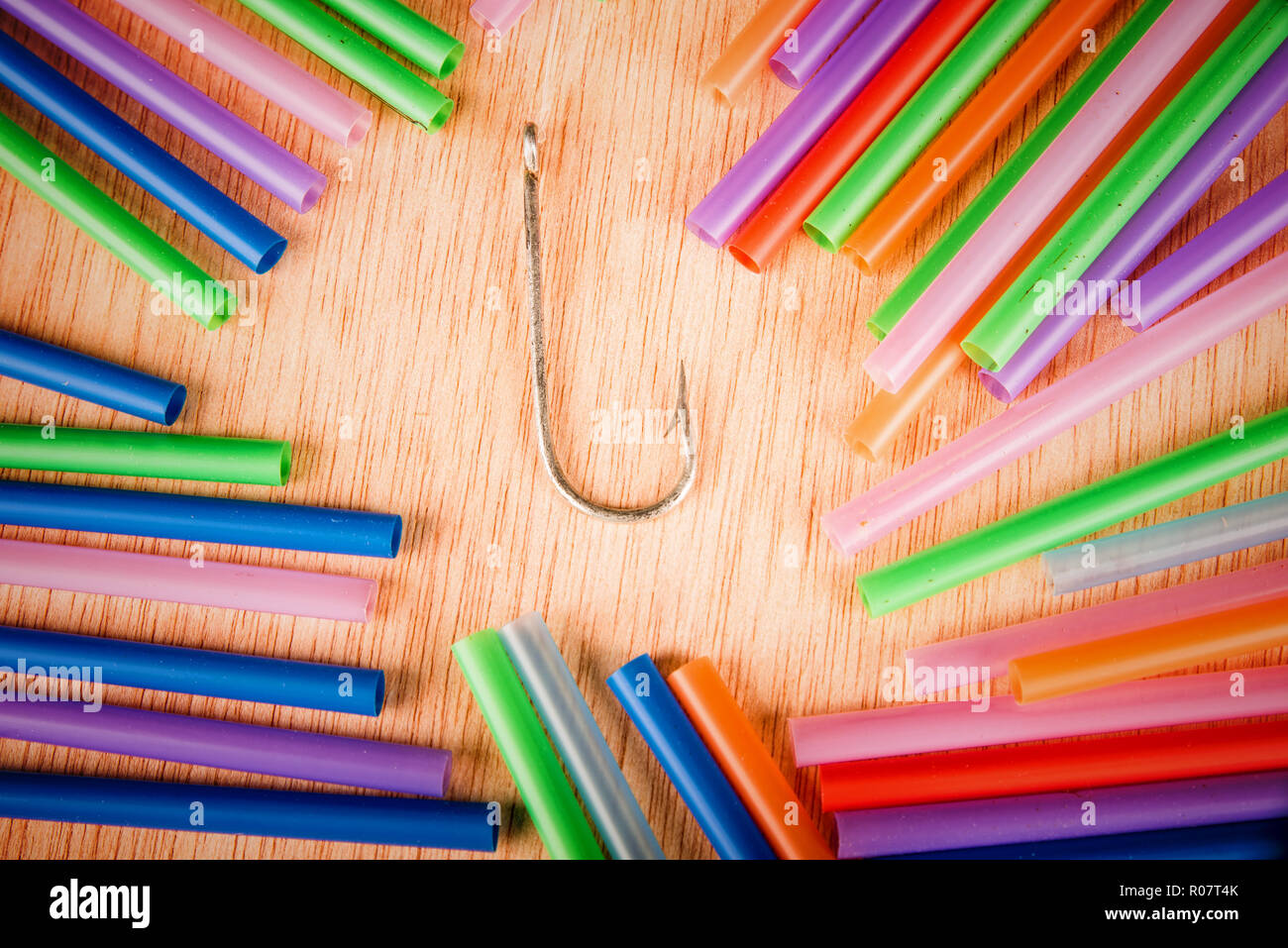 Fishing hook surrounded by drinking straws, a concept of the pollution