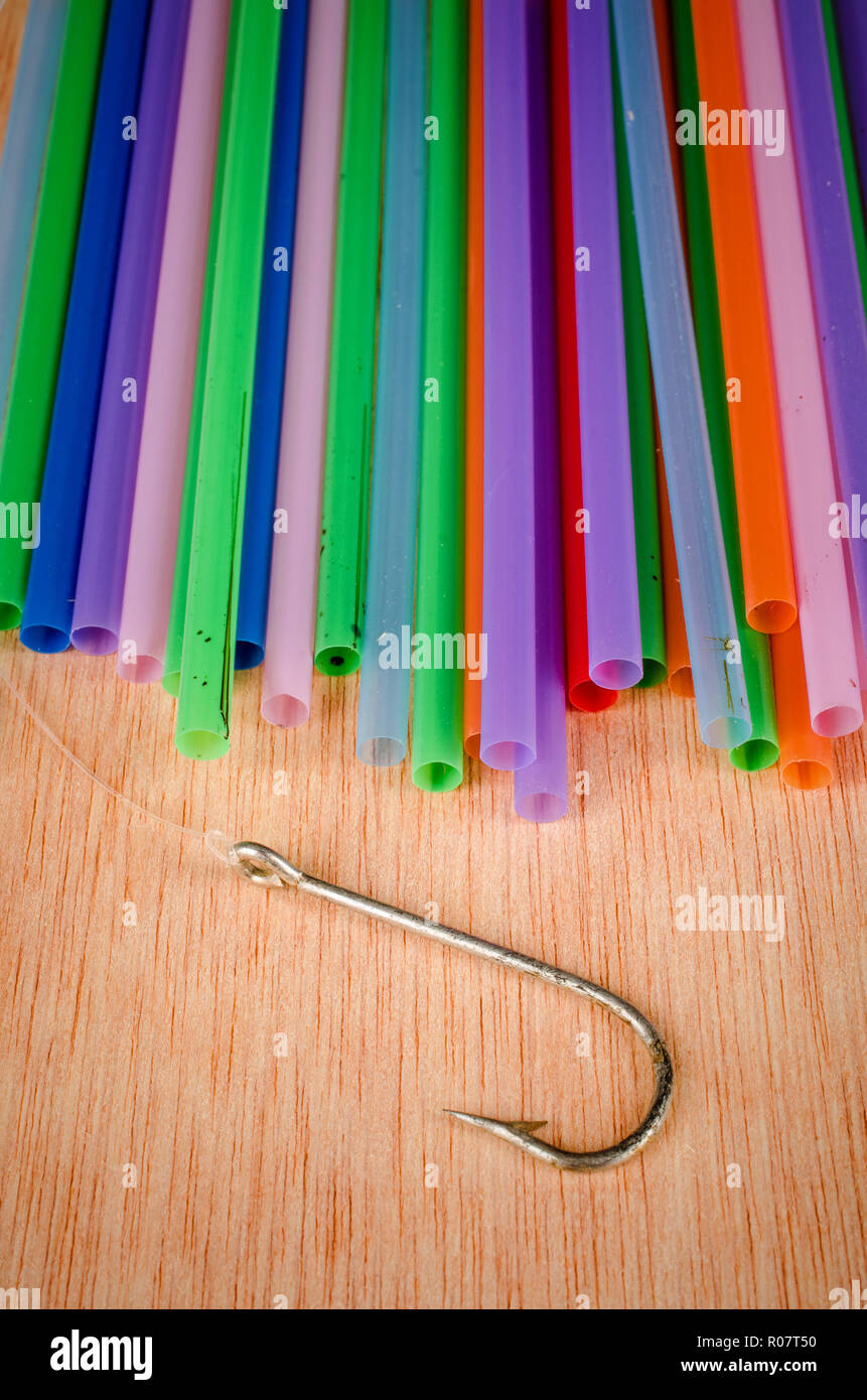 Fishing hook surrounded by drinking straws, a concept of the pollution