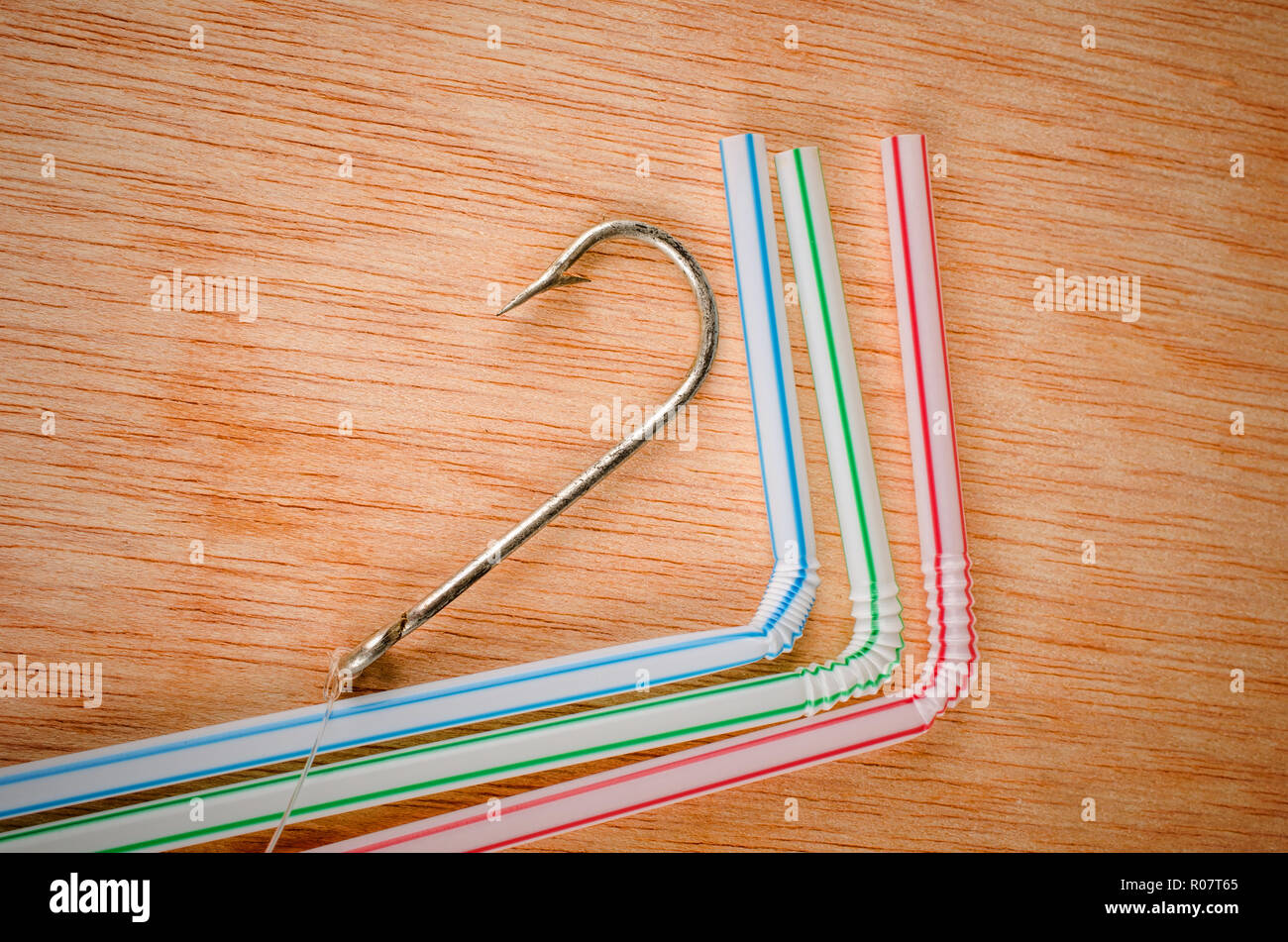 Fishing hook surrounded by drinking straws, a concept of the pollution