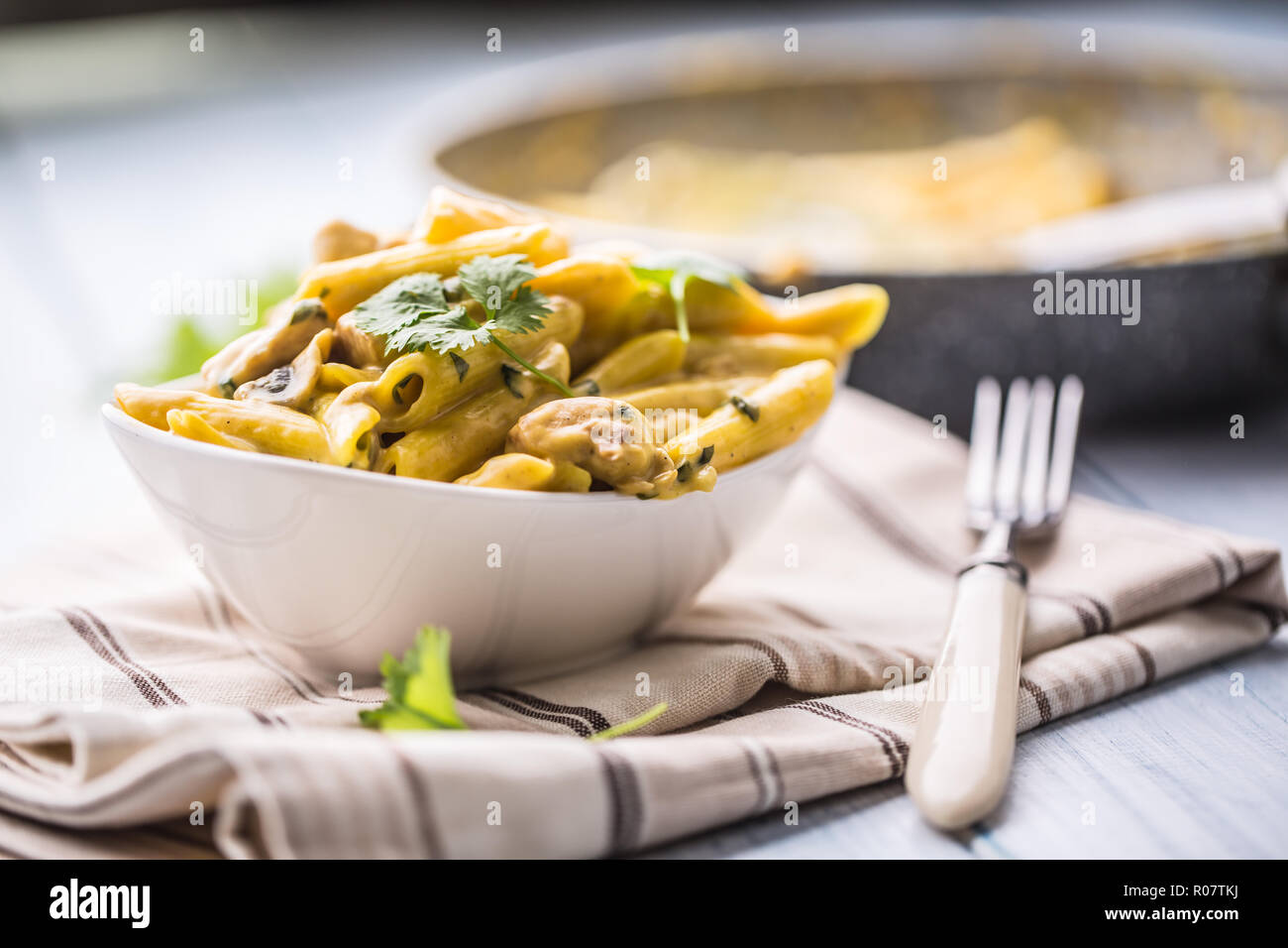 Pasta pene with chicken pieces mushrooms parmesan cheese sauce and herb decoration. Pene con pollo - Italian or medierranean cuisine. Stock Photo