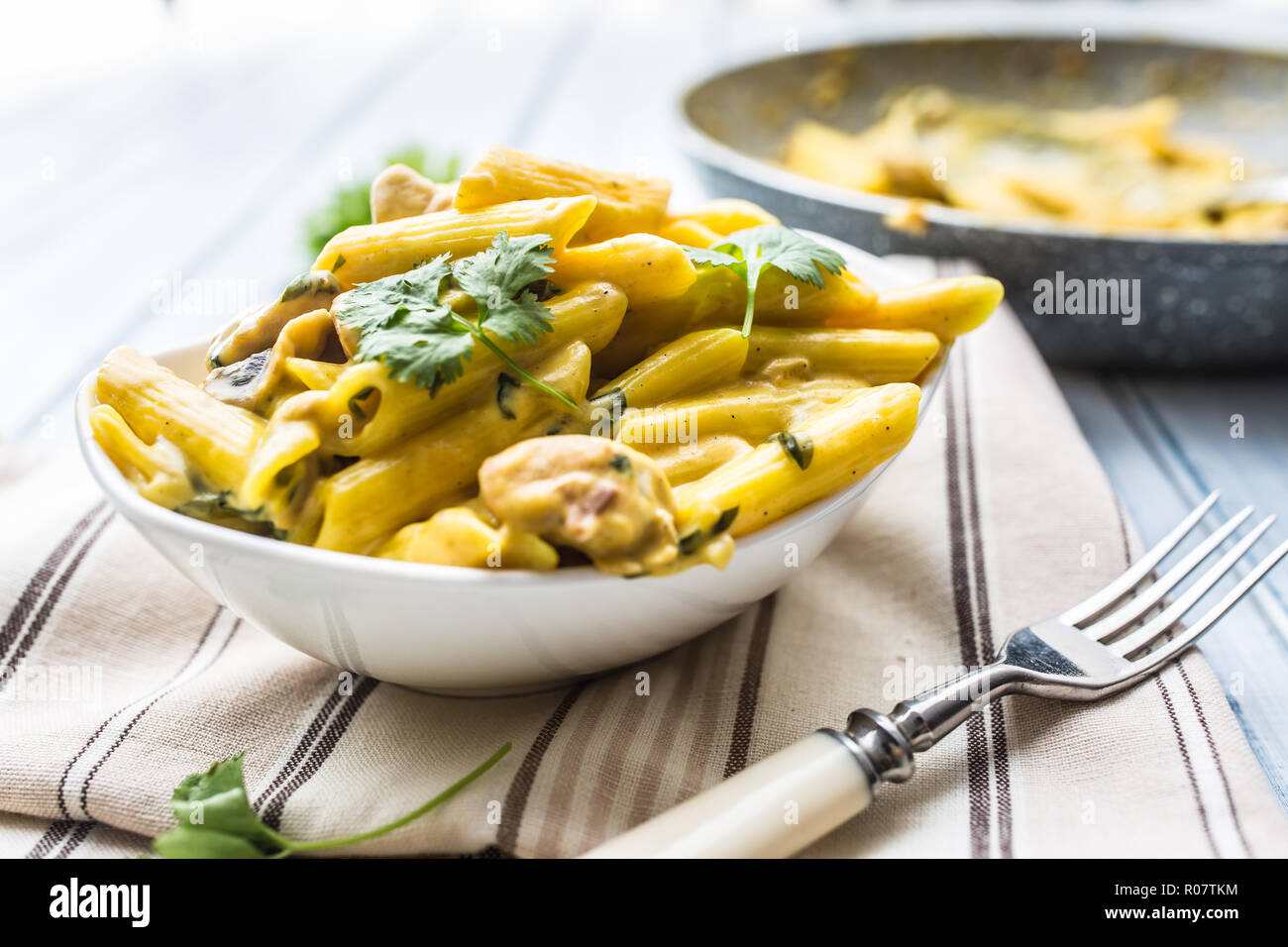 Pasta pene with chicken pieces mushrooms parmesan cheese sauce and herb decoration. Pene con pollo - Italian or medierranean cuisine. Stock Photo