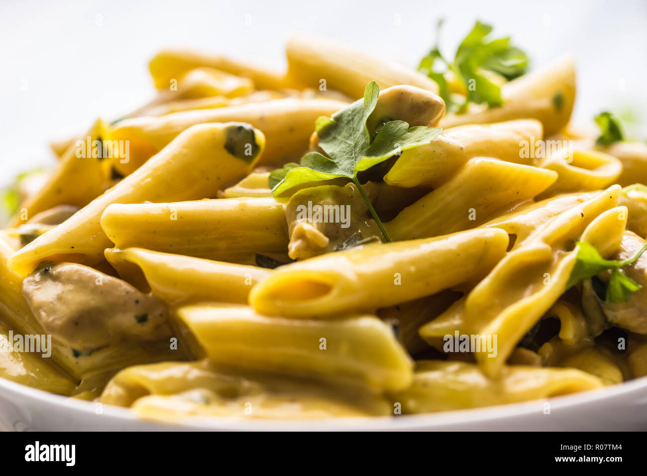 Pasta pene with chicken pieces mushrooms parmesan cheese sauce and herb decoration. Pene con pollo - Italian or medierranean cuisine. Stock Photo