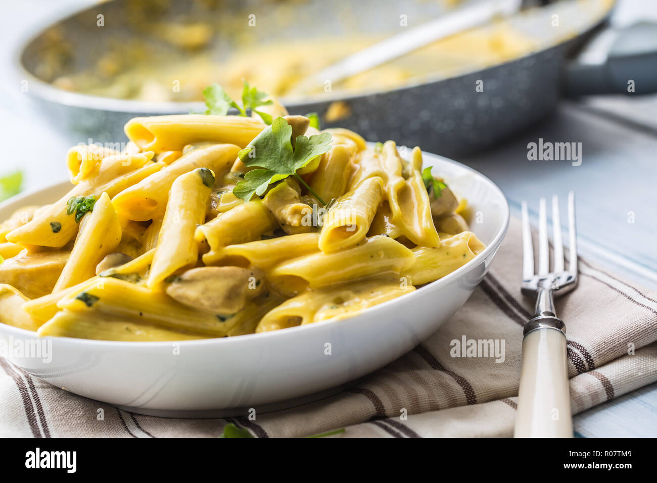 Pasta pene with chicken pieces mushrooms parmesan cheese sauce and herb decoration. Pene con pollo - Italian or medierranean cuisine. Stock Photo
