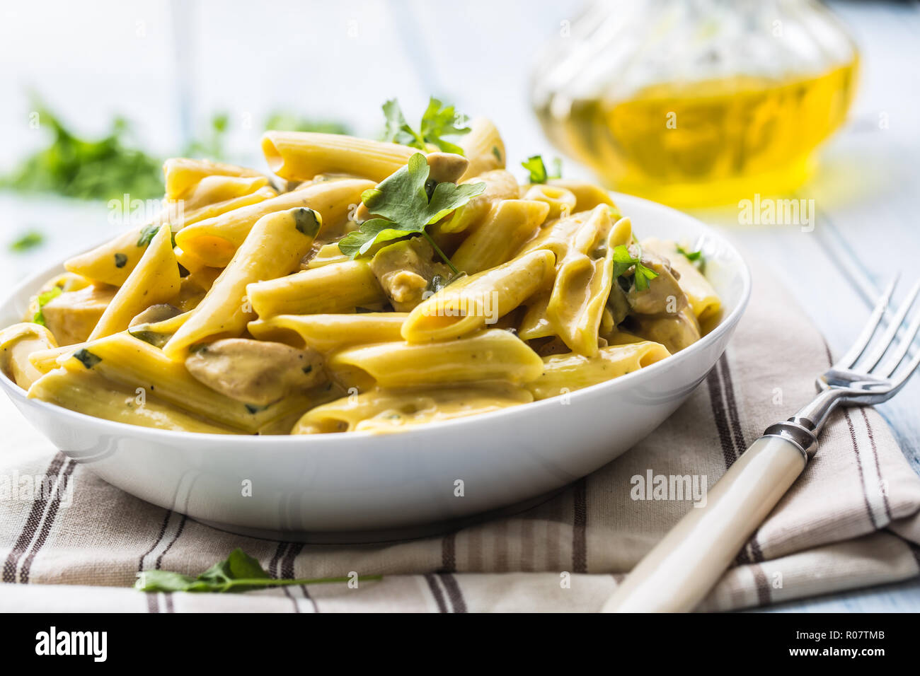 Pasta pene with chicken pieces mushrooms parmesan cheese sauce and herb decoration. Pene con pollo - Italian or medierranean cuisine. Stock Photo