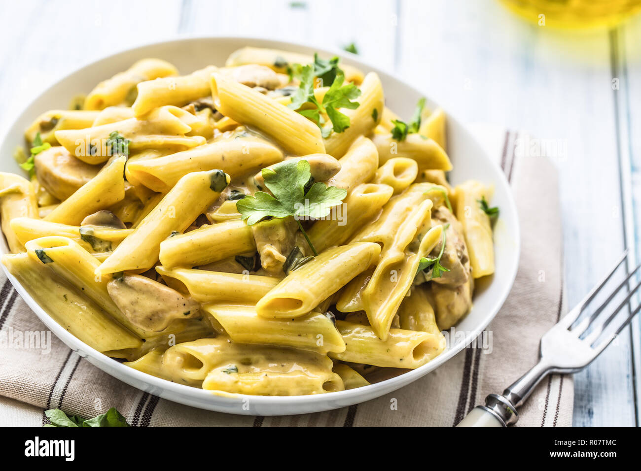 Pasta pene with chicken pieces mushrooms parmesan cheese sauce and herb decoration. Pene con pollo - Italian or medierranean cuisine. Stock Photo