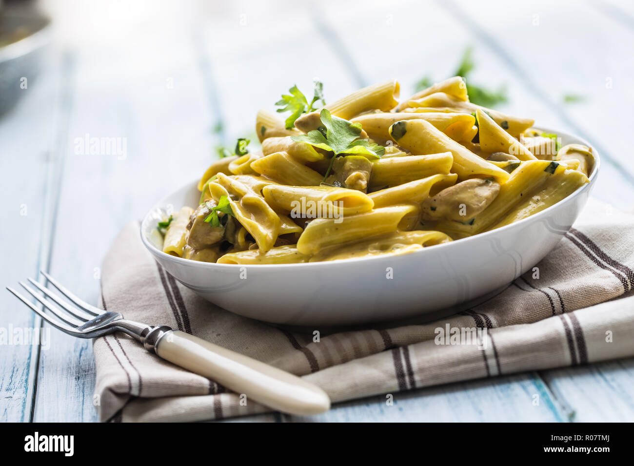 Pasta pene with chicken pieces mushrooms parmesan cheese sauce and herb decoration. Pene con pollo - Italian or medierranean cuisine. Stock Photo