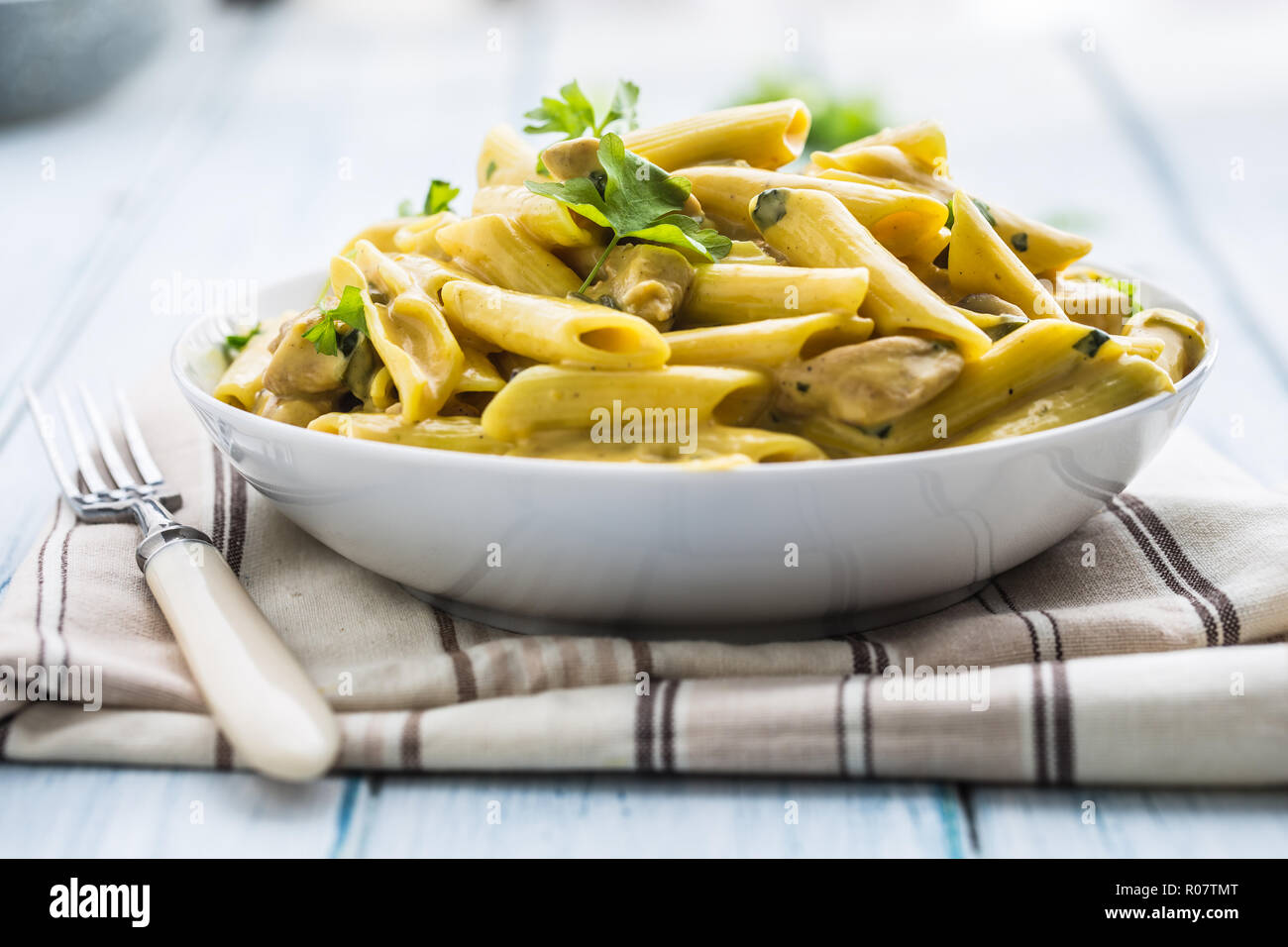 Pasta pene with chicken pieces mushrooms parmesan cheese sauce and herb decoration. Pene con pollo - Italian or medierranean cuisine. Stock Photo