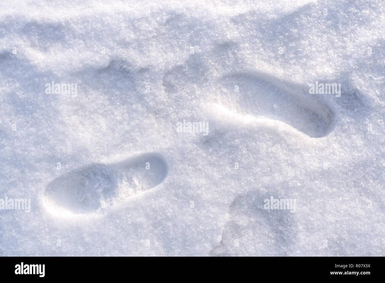Two human foot shoes prints on white freshly fallen snow.  Stock Photo