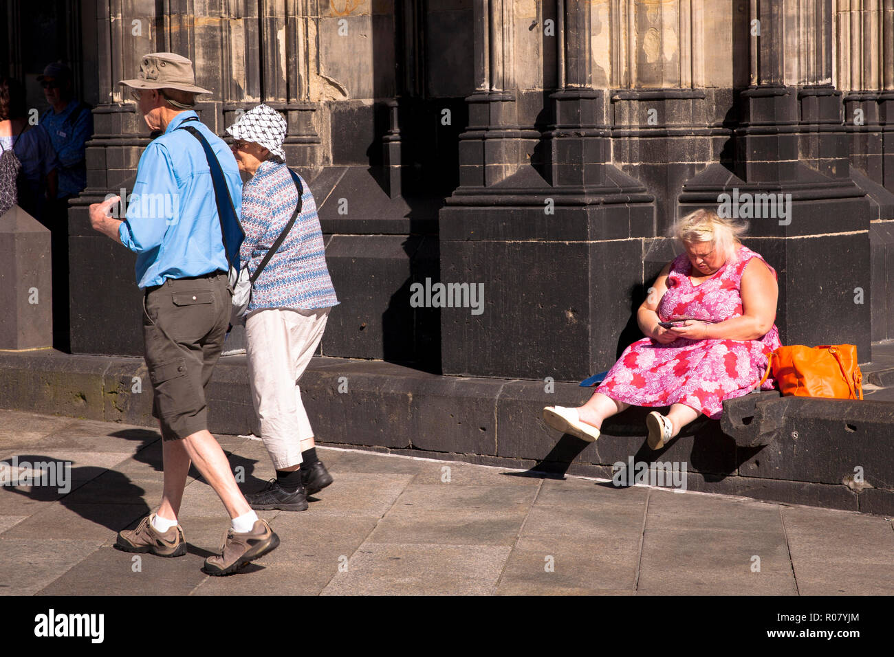 woman is sitting at the cathedral, passer-by, Cologne, Germany.  Frau sitzt am Dom, Passanten, Koeln, Deutschland. Stock Photo