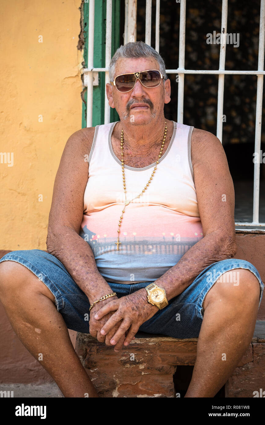 TRINIDAD, CUBA - APR 02, 2017: A cuban with golden accessories sitting in Trinidad Stock Photo
