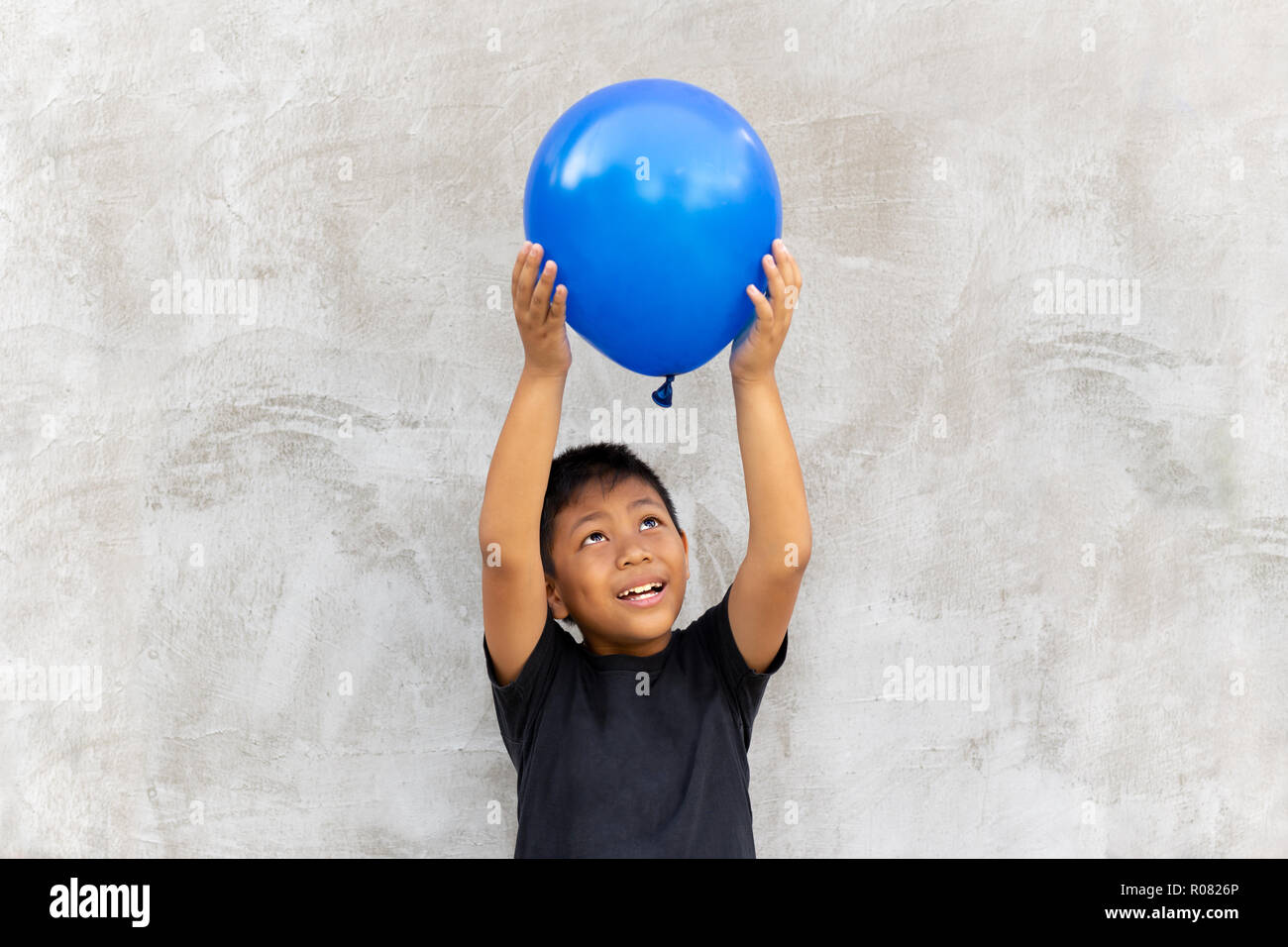Asian boy play catches balloon on grey background Stock Photo - Alamy