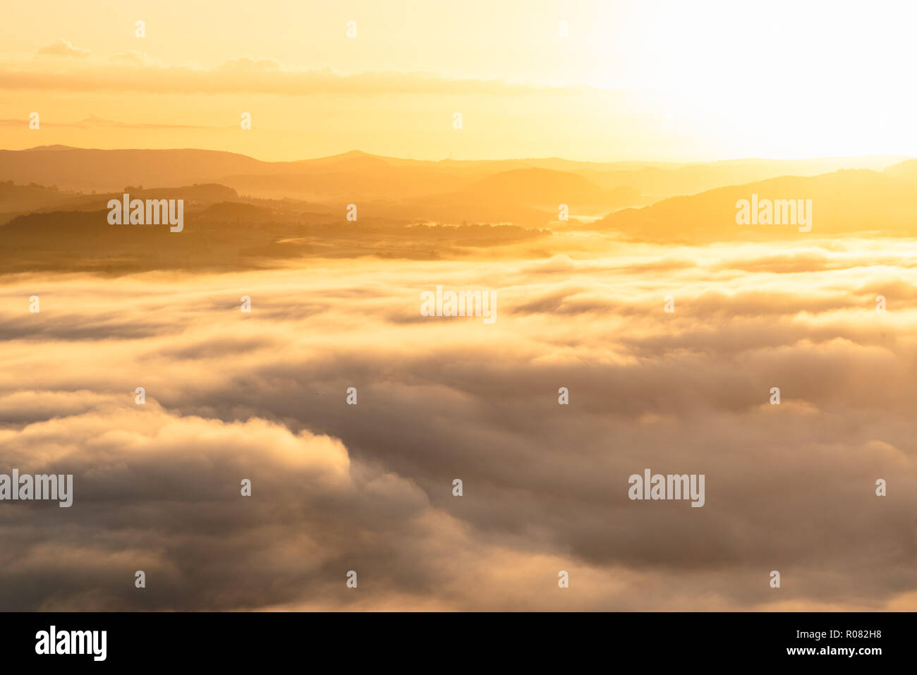 first sunrays of the day turn the clouds over the Elbe Santstone National park in golden light, Eastern Saxony, Germany Stock Photo