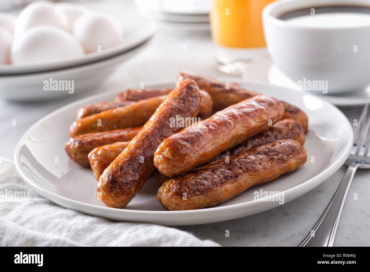A plate of delicious cooked breakfast sausage with coffee, orange juice and eggs. Stock Photo