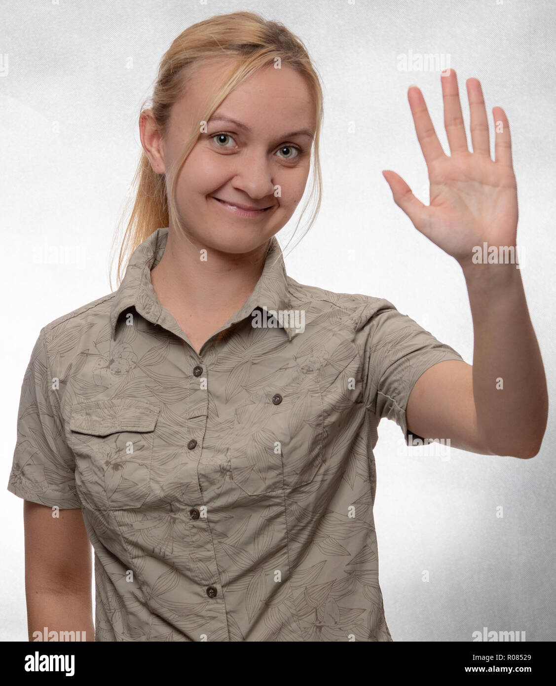 young woman in trekking shirt with hand up Stock Photo