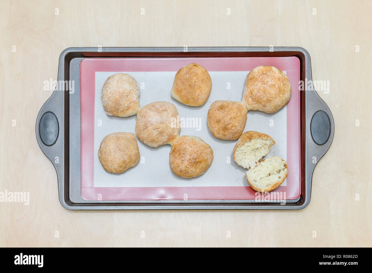 freshly baked buns on a silicone baking mat, on an iron tray Stock Photo