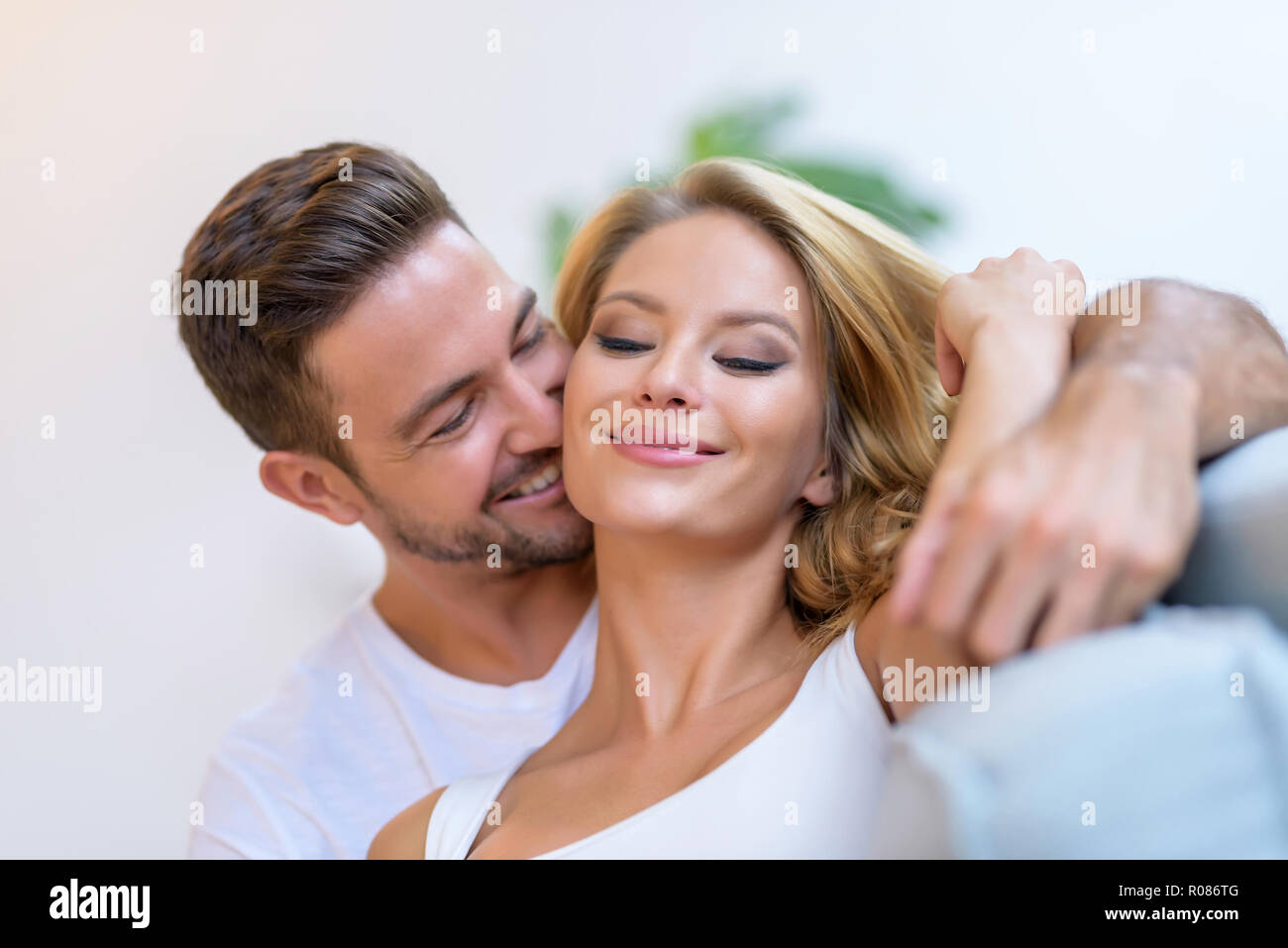 A beautiful young woman lying on the sofa with boyfriend hugging her ...