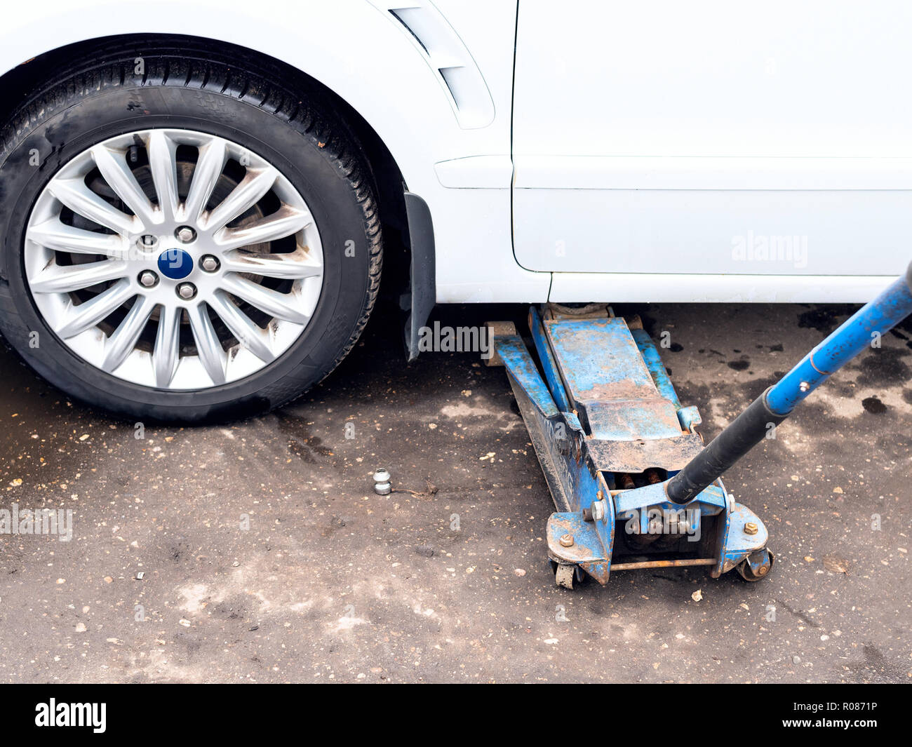 hydraulic jack lifts a vehicle outdoors for seasonal replacement of