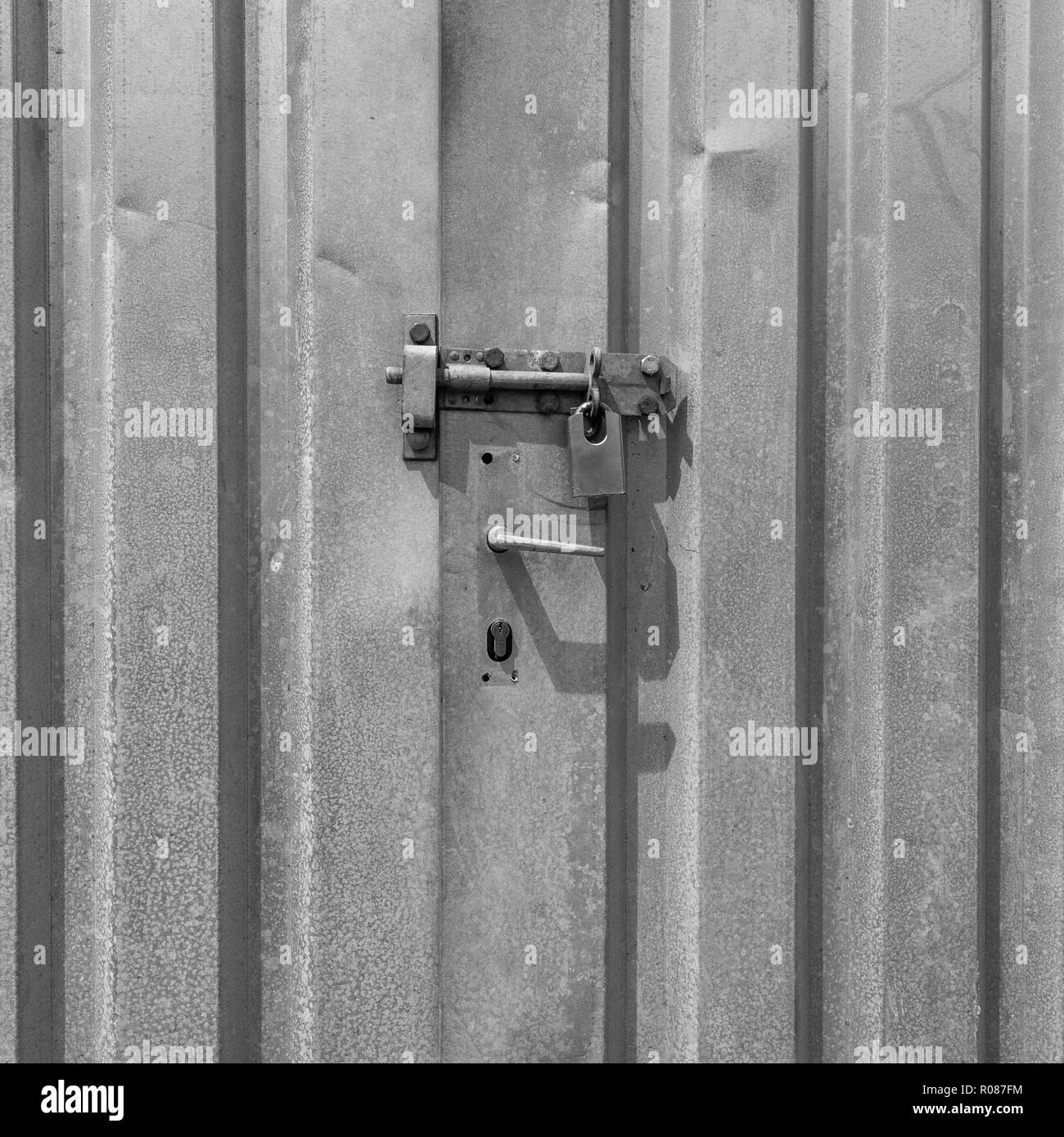 Padlocked doors of lock-up self-storage shipping contained. Metaphor for secure, data security, virus protection, lockdown etc. B&W version of R086F0. Stock Photo