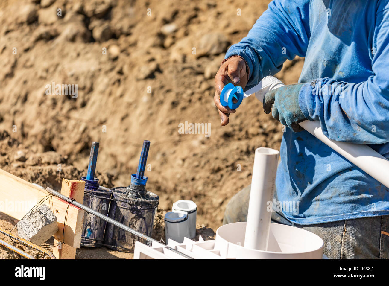 Plumber Applying PTFE Tape To PVC Pipe At Construction Site Stock Photo