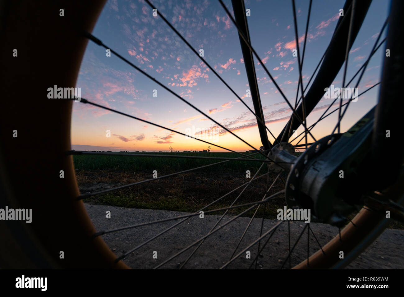 A colorful sunset in Holland as seen through the wheel of a bicycle Stock Photo