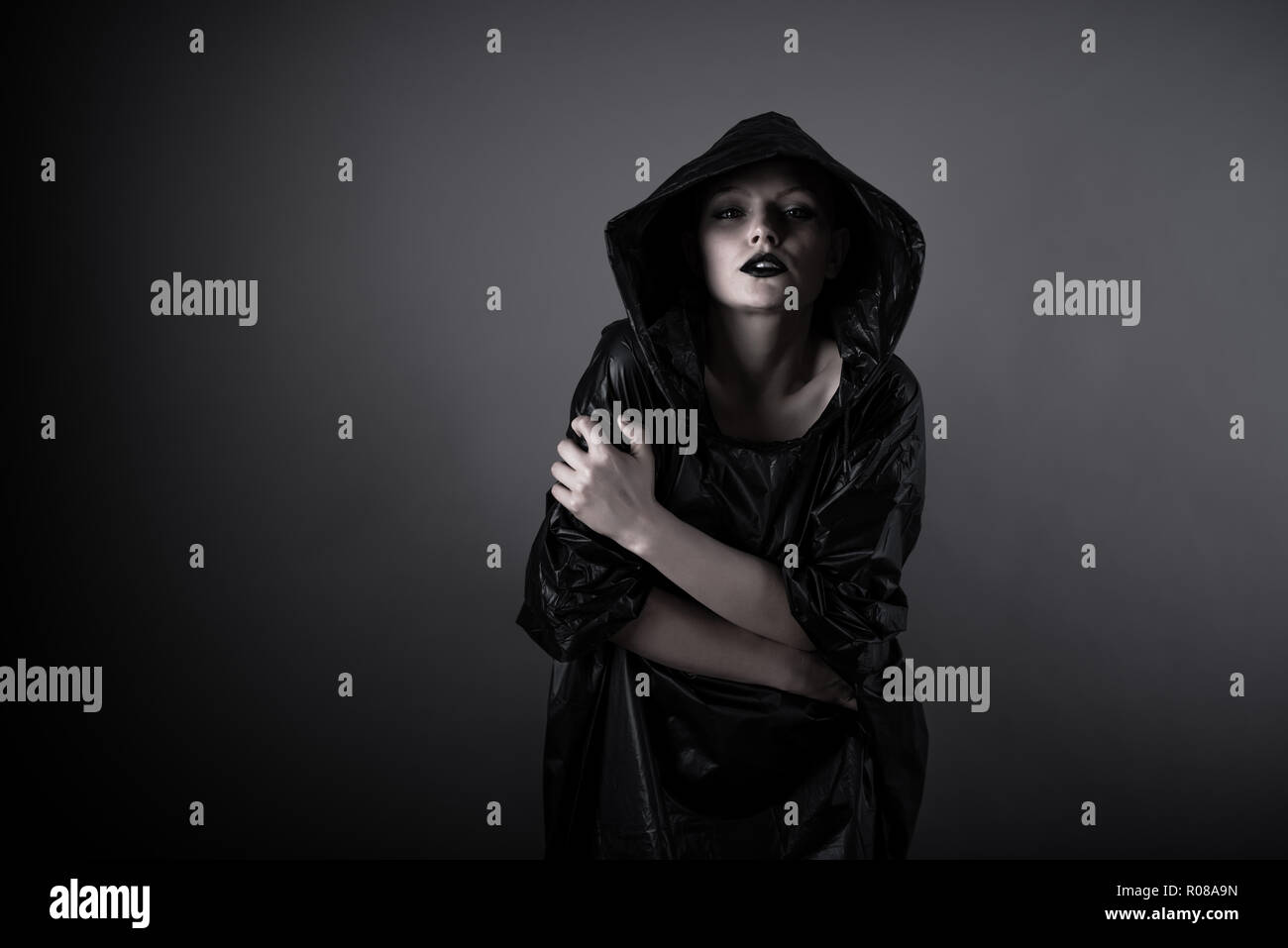Emotive photo of a beautiful bald woman in a black raincoat with the ...