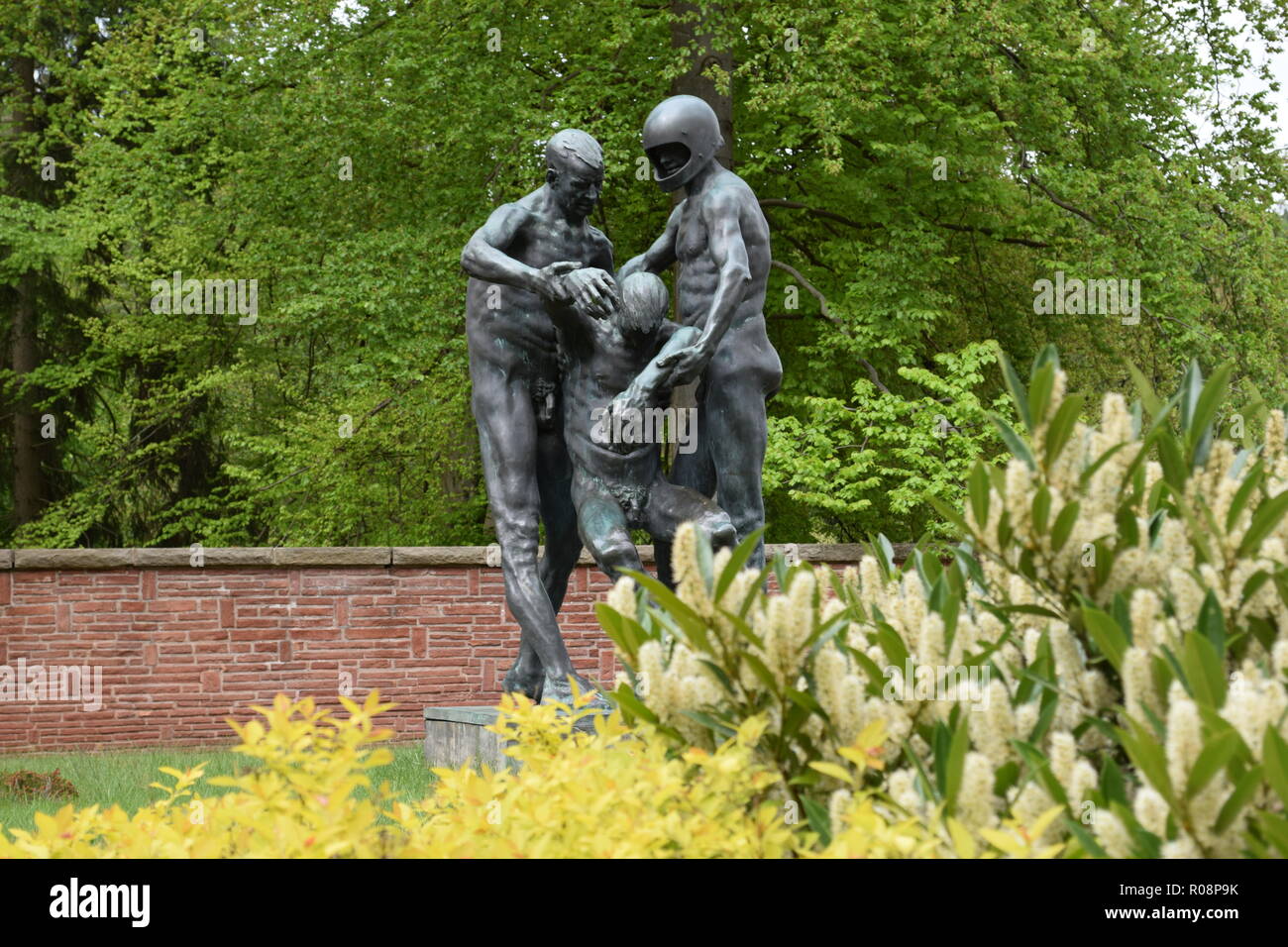 A bronze statue in summer at the War War 2 Cemetery in Reimsbach depicts two men carrying a deadly victim as a symbol of the helplessness of man. Stock Photo