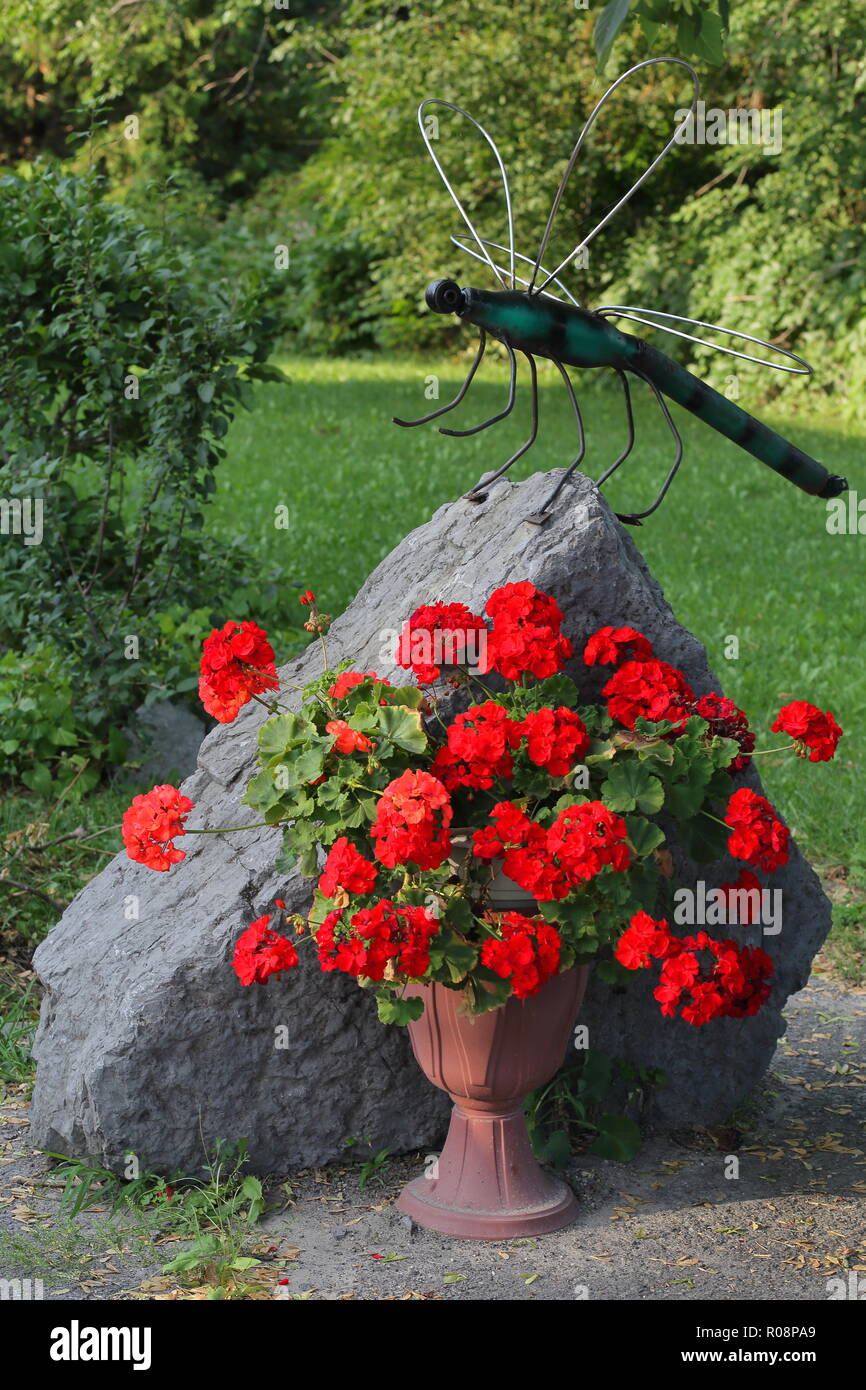 Garden decorations - stone and dragonfly plus flowers Stock Photo