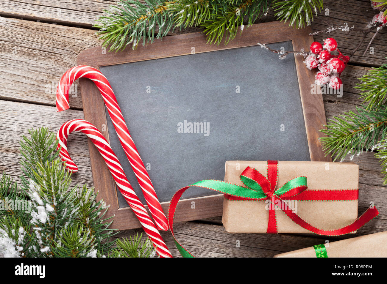Christmas gift box, candy cane and snow fir tree on wooden table. Top ...