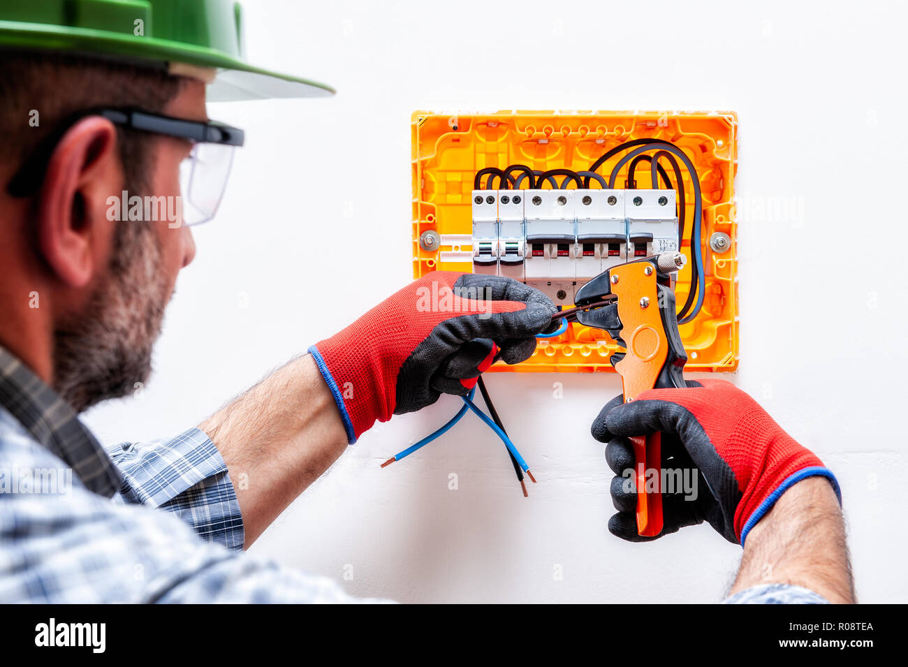 Electrician technician with helmet, goggles and gloves protected hands ...