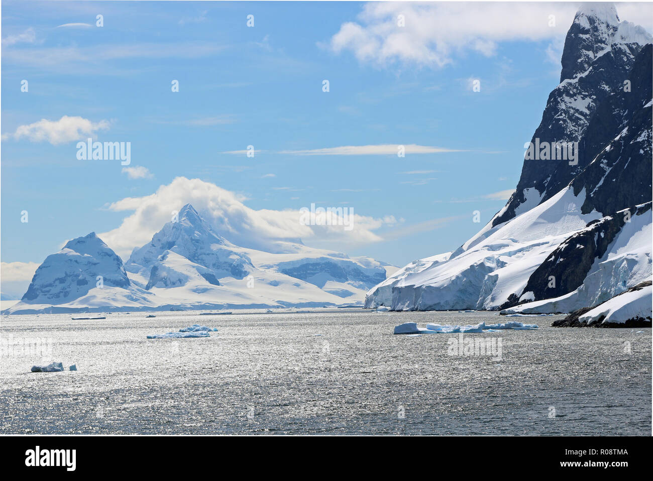 Shimmering snows of the peaks surrounding the glistening waters of the stunning Lemaire Channel, Antarctic Peninsula Stock Photo
