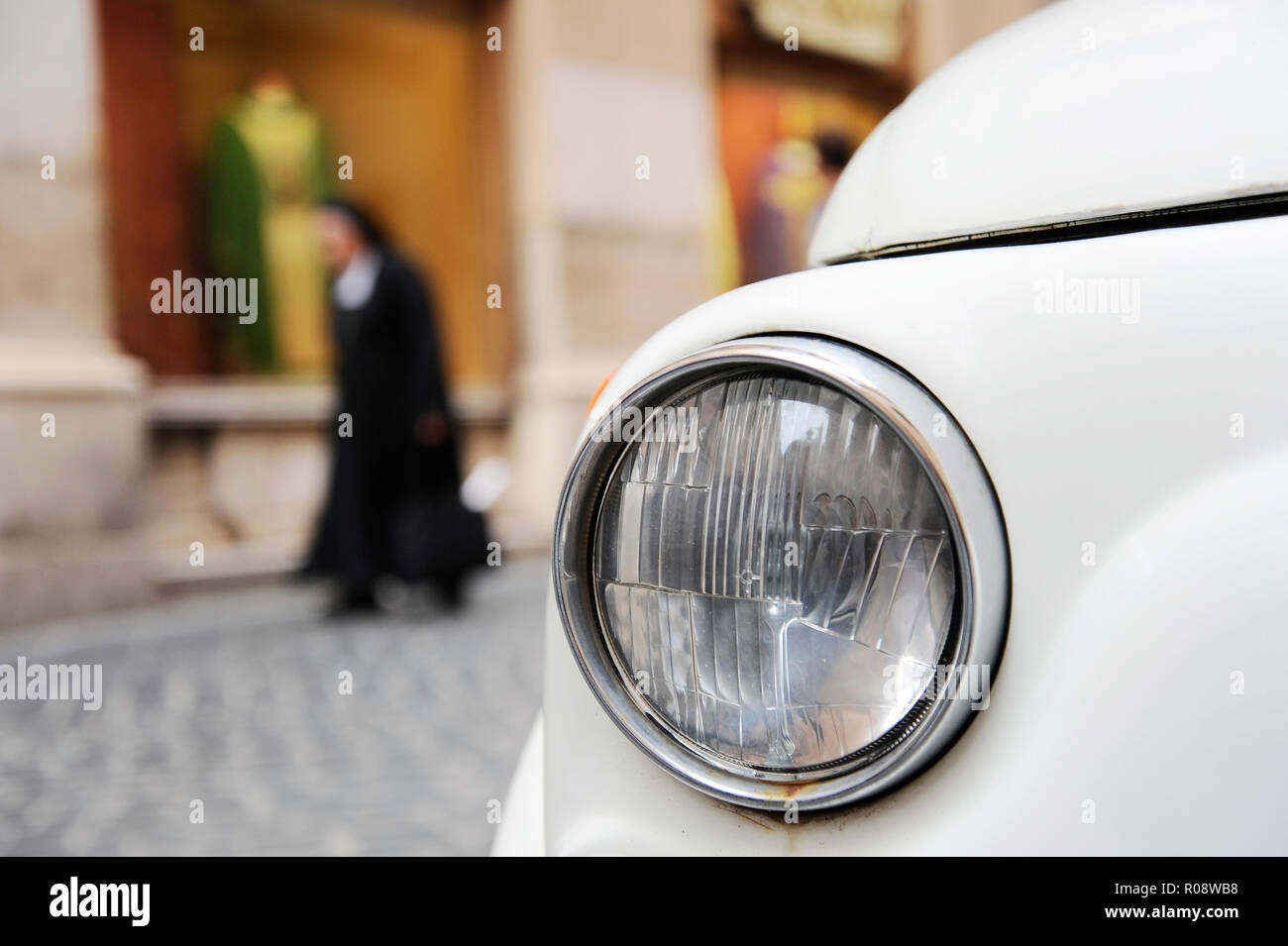 A parked Fiat 500 in the streets of Rome, a nun walking on the ...