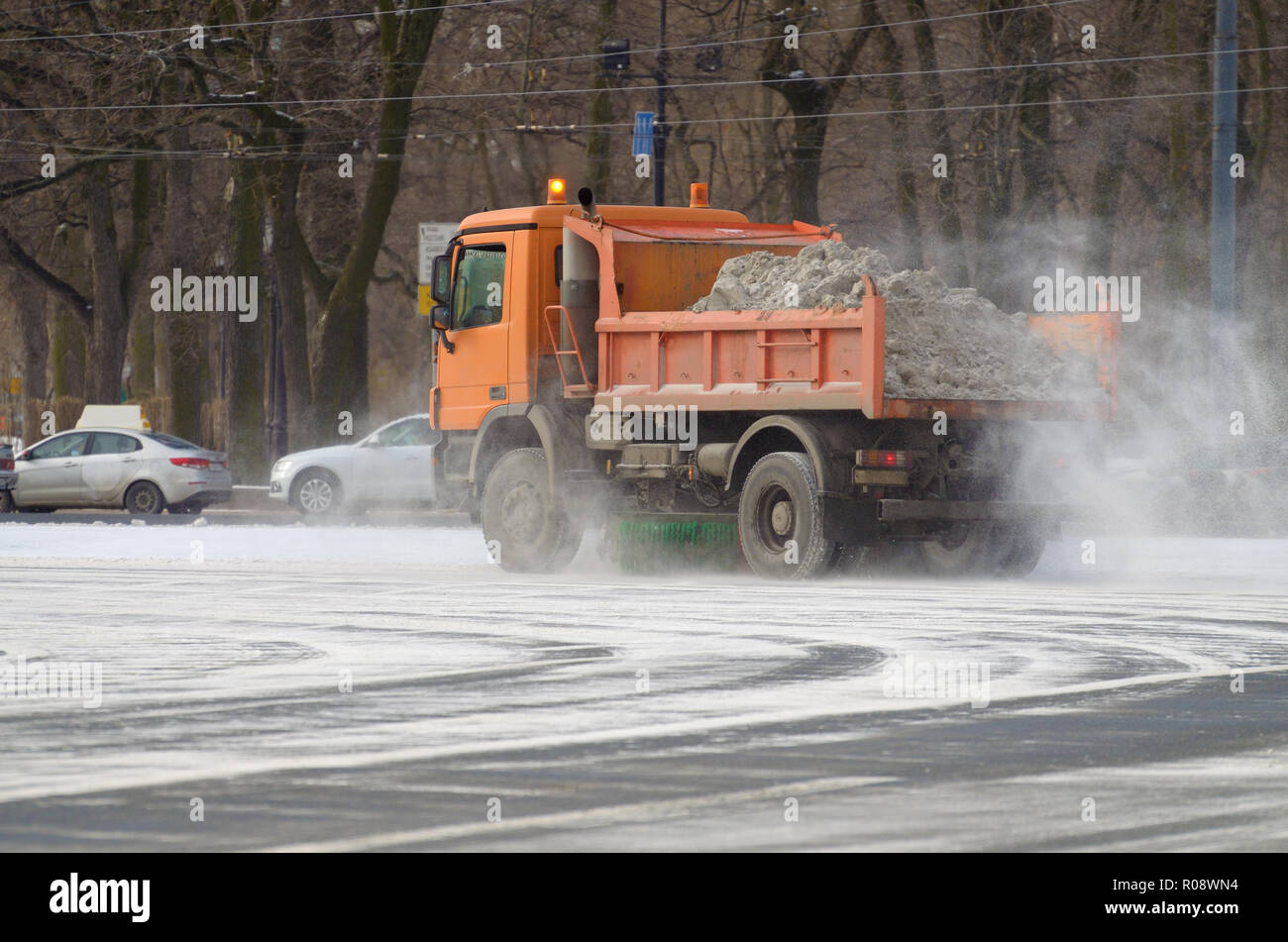 Night in the city the snow fell.His cleaning went snow-removal vehicles.They cleared the roads on the streets of the city. Stock Photo