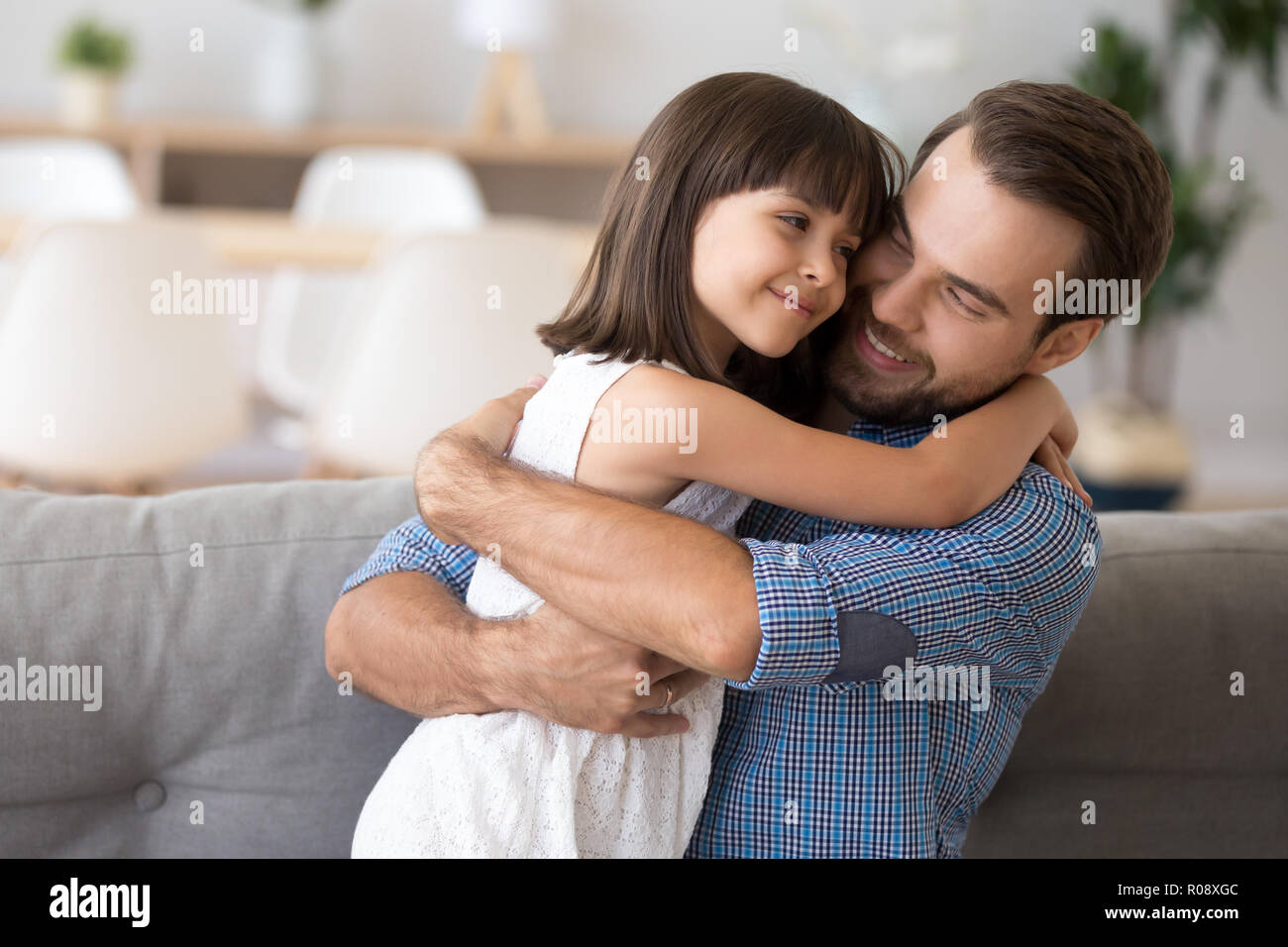 Little daughter looking at father with love embracing him Stock Photo